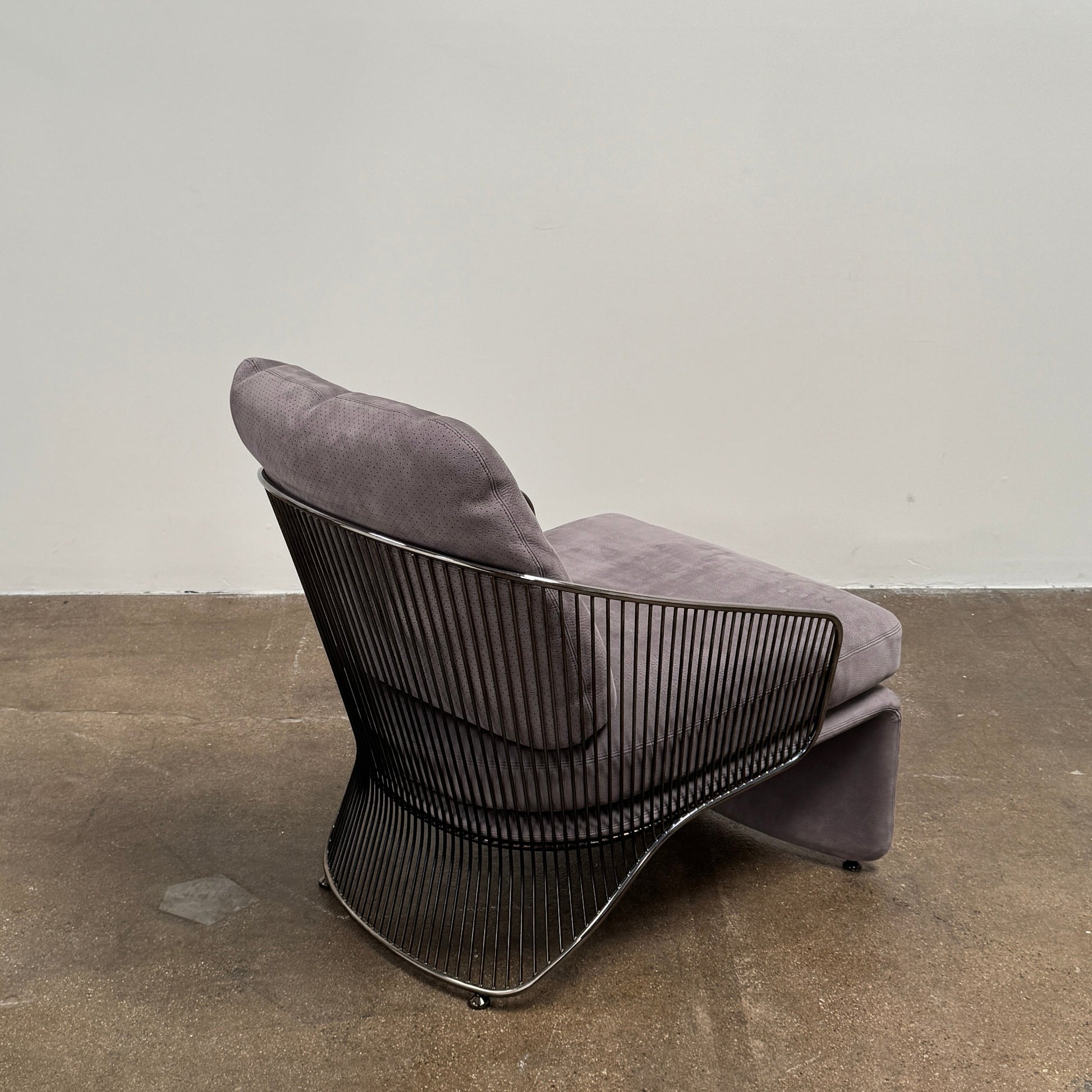 A set of two Minotti Colette Lounge Chairs by Minotti is displayed side by side against a plain white background. Each chair showcases luxurious gray nubuck leather upholstery and sleek black metal armrests, elegantly capturing the timeless mid-century silhouette characteristic of the iconic design.