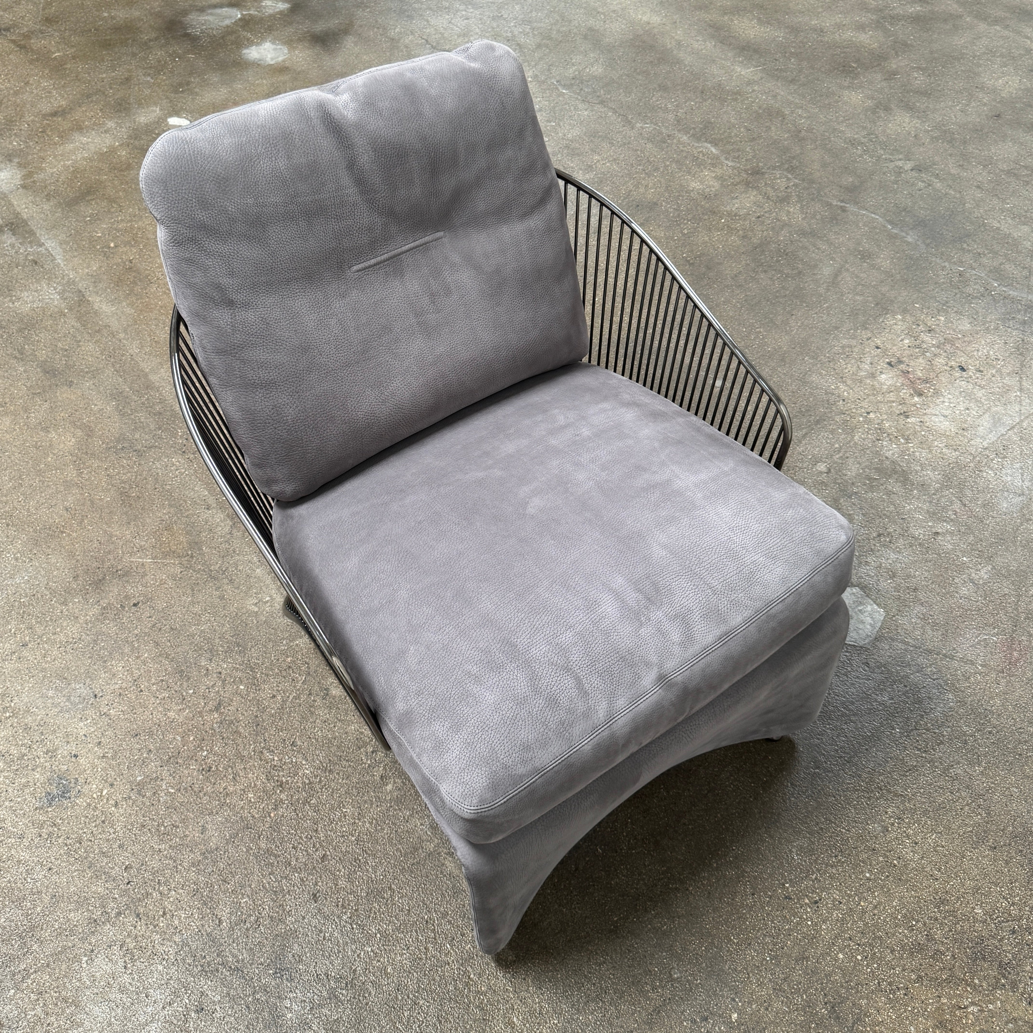 A set of two Minotti Colette Lounge Chairs by Minotti is displayed side by side against a plain white background. Each chair showcases luxurious gray nubuck leather upholstery and sleek black metal armrests, elegantly capturing the timeless mid-century silhouette characteristic of the iconic design.