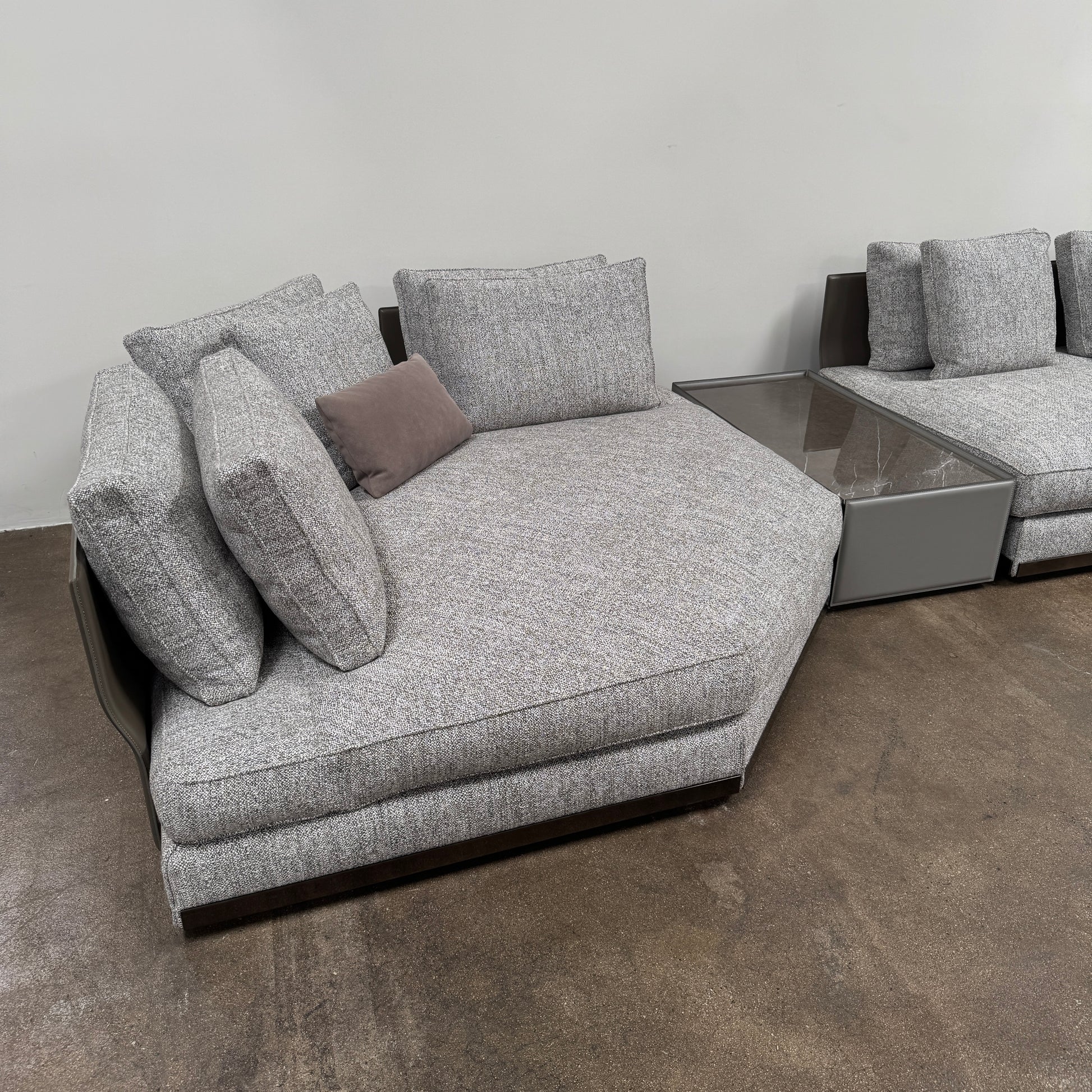The Minotti West Sectional Sofa with Side Table and Clive Bench by Minotti features a large, L-shaped modern design with gray upholstery, multiple plush cushions, and an integrated side table—perfect for elevating luxury living rooms—all set against a plain white background.