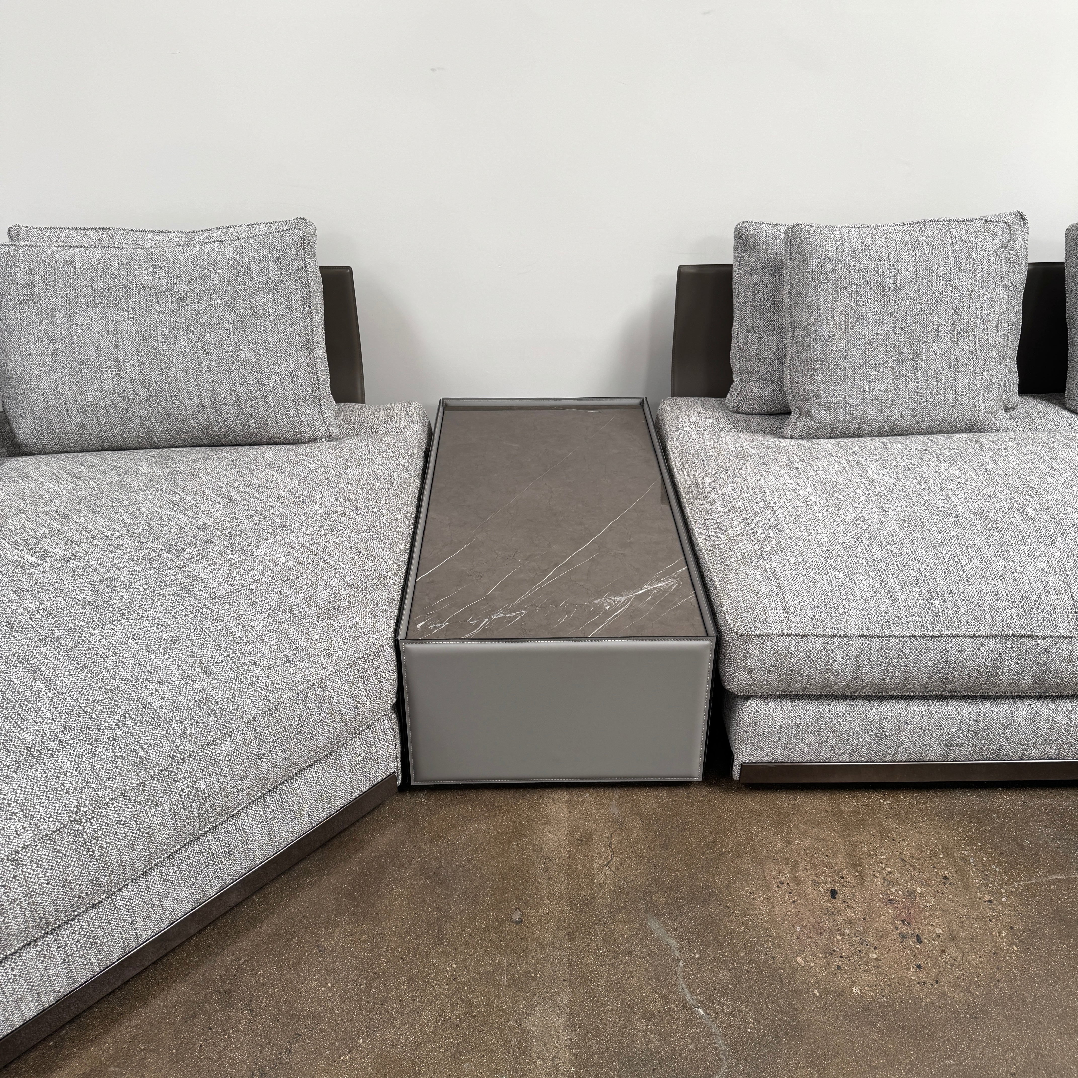 The Minotti West Sectional Sofa with Side Table and Clive Bench by Minotti features a large, L-shaped modern design with gray upholstery, multiple plush cushions, and an integrated side table—perfect for elevating luxury living rooms—all set against a plain white background.