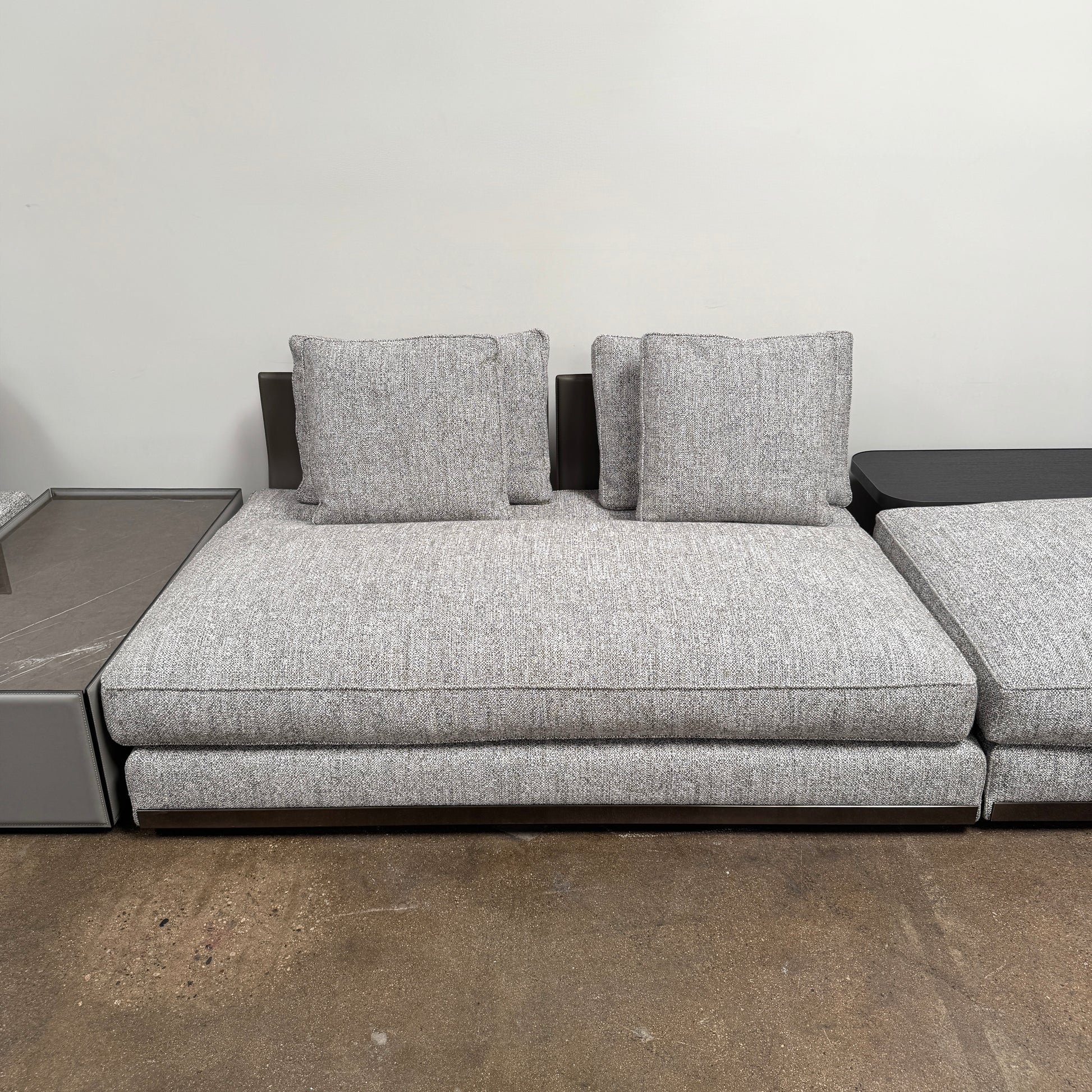 The Minotti West Sectional Sofa with Side Table and Clive Bench by Minotti features a large, L-shaped modern design with gray upholstery, multiple plush cushions, and an integrated side table—perfect for elevating luxury living rooms—all set against a plain white background.