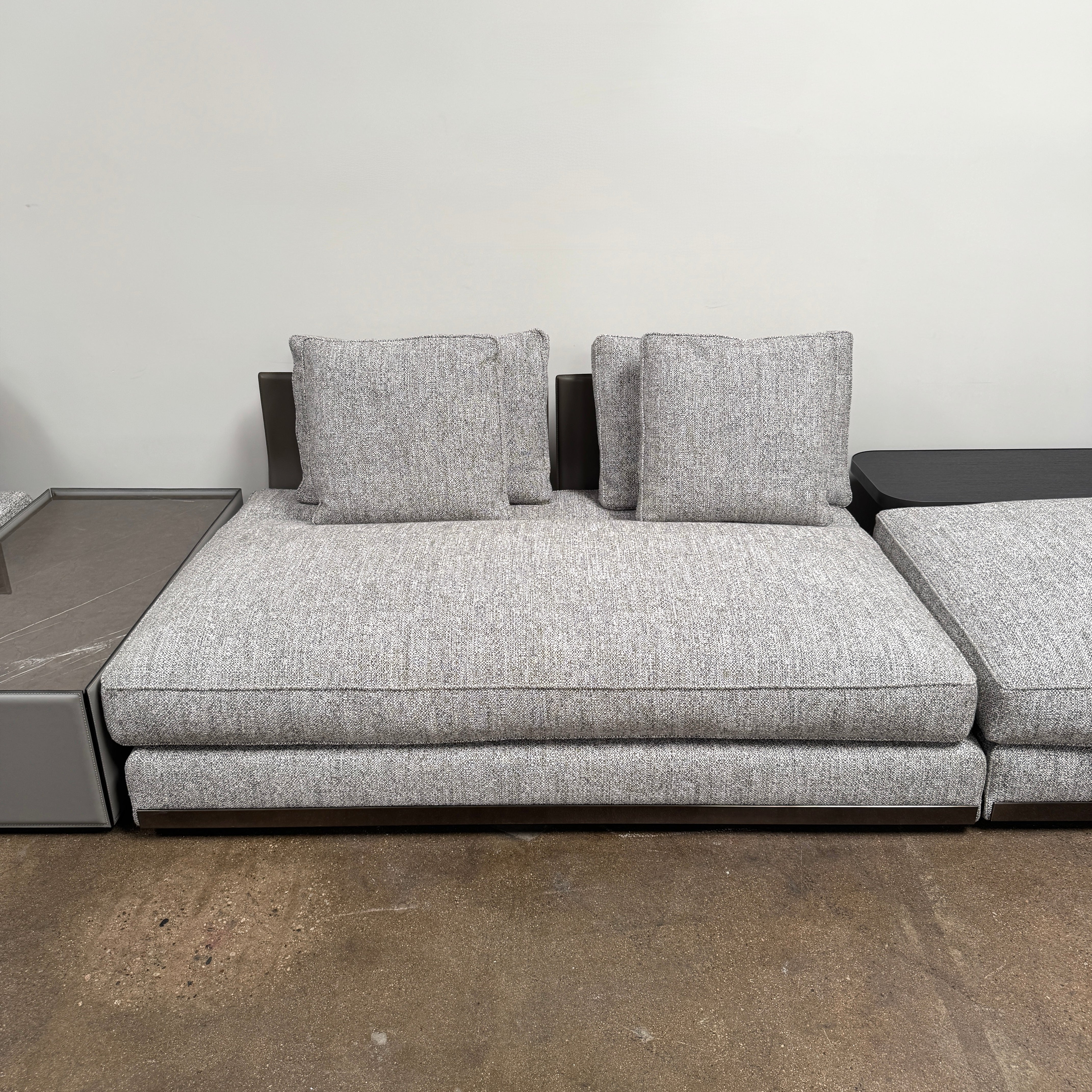 The Minotti West Sectional Sofa with Side Table and Clive Bench by Minotti features a large, L-shaped modern design with gray upholstery, multiple plush cushions, and an integrated side table—perfect for elevating luxury living rooms—all set against a plain white background.