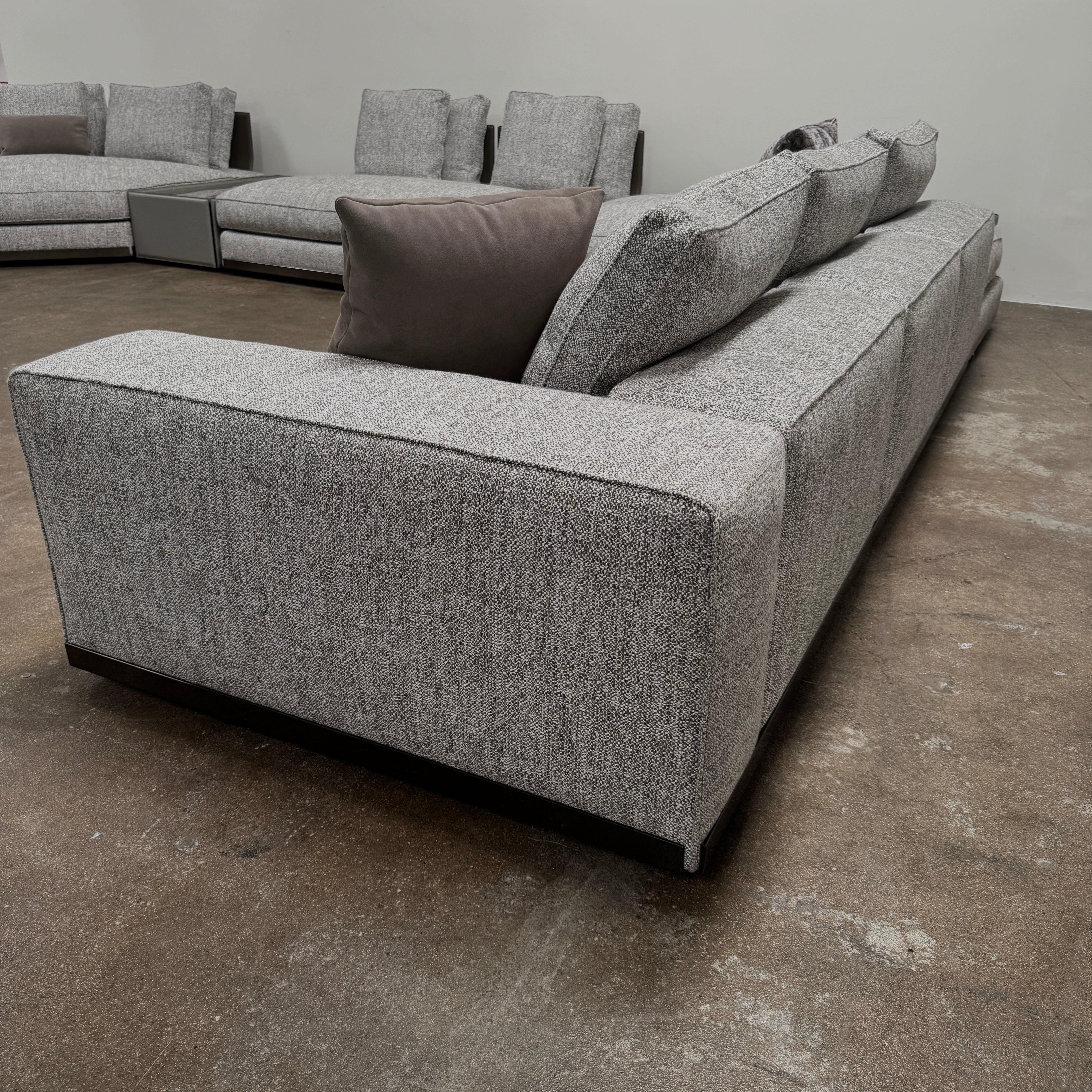 The Minotti West Sectional Sofa with Side Table and Clive Bench by Minotti features a large, L-shaped modern design with gray upholstery, multiple plush cushions, and an integrated side table—perfect for elevating luxury living rooms—all set against a plain white background.