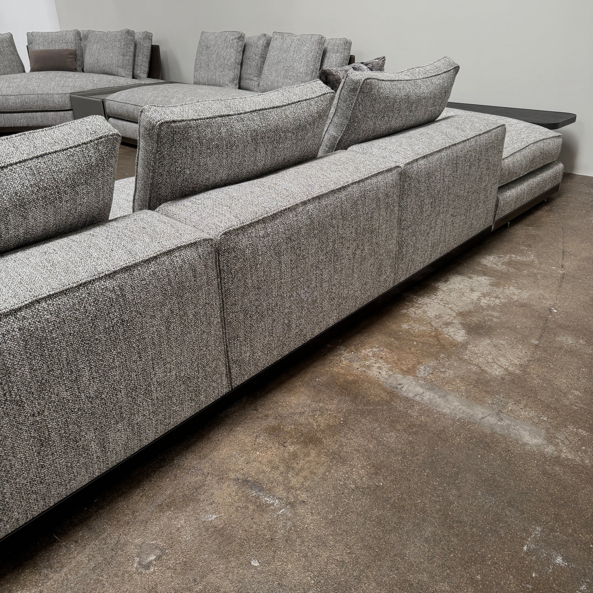 The Minotti West Sectional Sofa with Side Table and Clive Bench by Minotti features a large, L-shaped modern design with gray upholstery, multiple plush cushions, and an integrated side table—perfect for elevating luxury living rooms—all set against a plain white background.