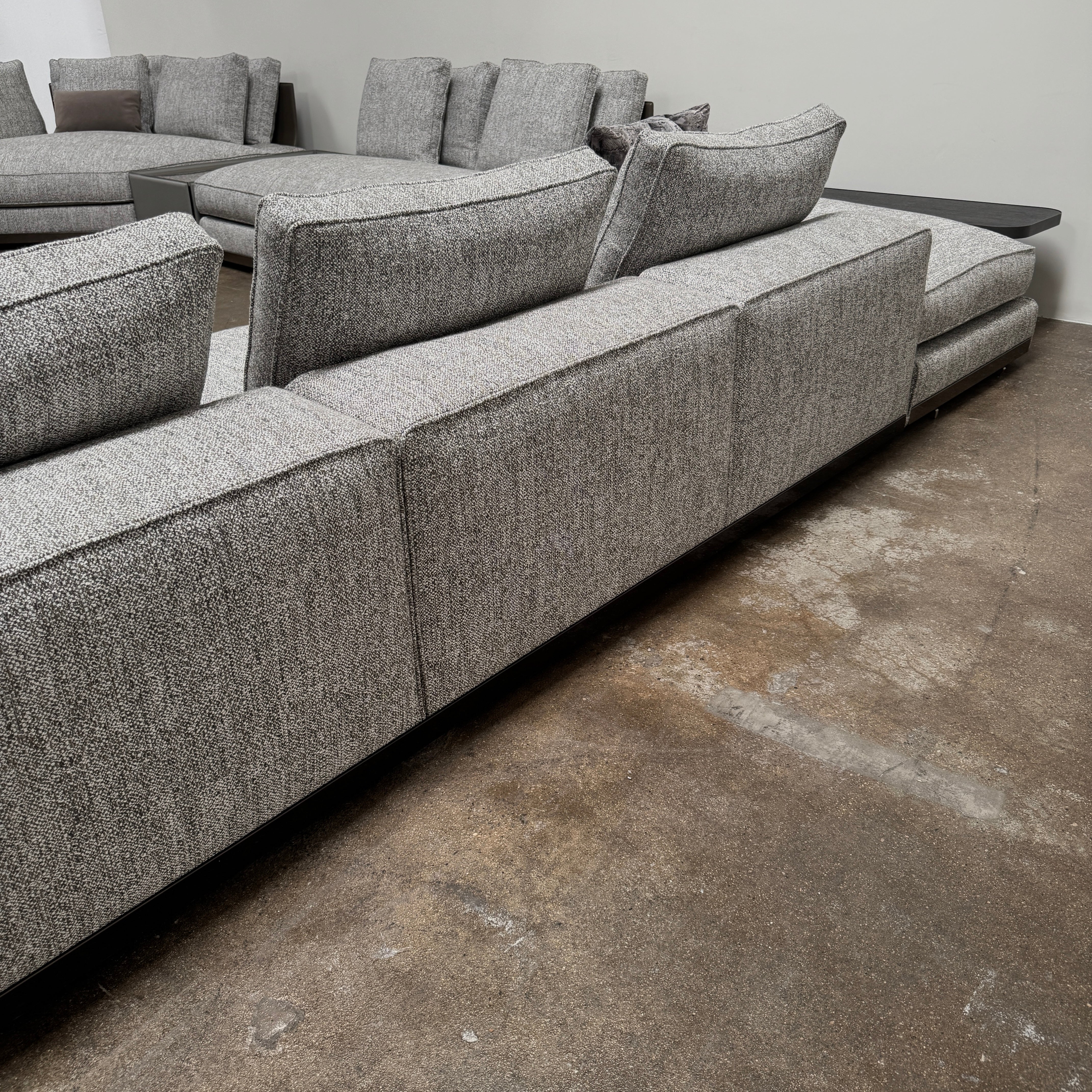 The Minotti West Sectional Sofa with Side Table and Clive Bench by Minotti features a large, L-shaped modern design with gray upholstery, multiple plush cushions, and an integrated side table—perfect for elevating luxury living rooms—all set against a plain white background.