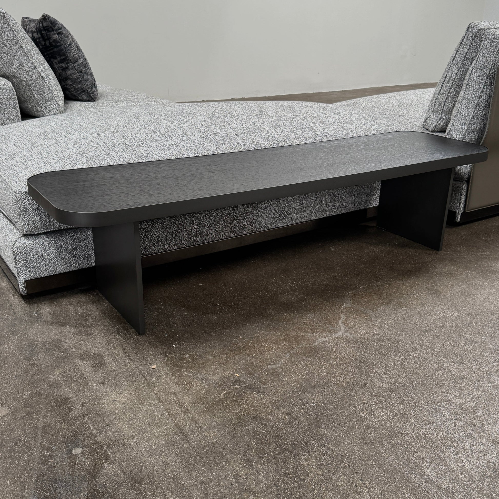 The Minotti West Sectional Sofa with Side Table and Clive Bench by Minotti features a large, L-shaped modern design with gray upholstery, multiple plush cushions, and an integrated side table—perfect for elevating luxury living rooms—all set against a plain white background.