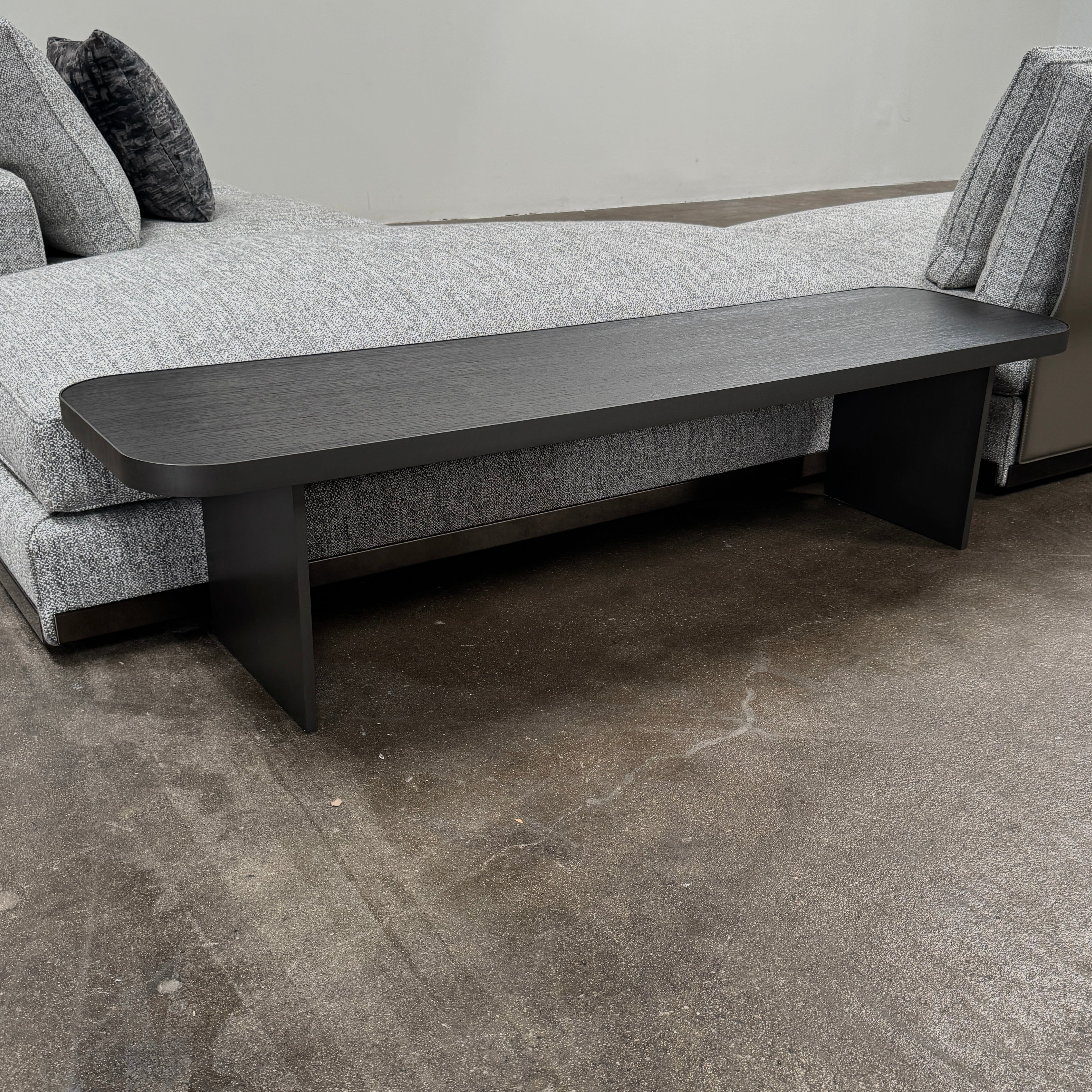 The Minotti West Sectional Sofa with Side Table and Clive Bench by Minotti features a large, L-shaped modern design with gray upholstery, multiple plush cushions, and an integrated side table—perfect for elevating luxury living rooms—all set against a plain white background.