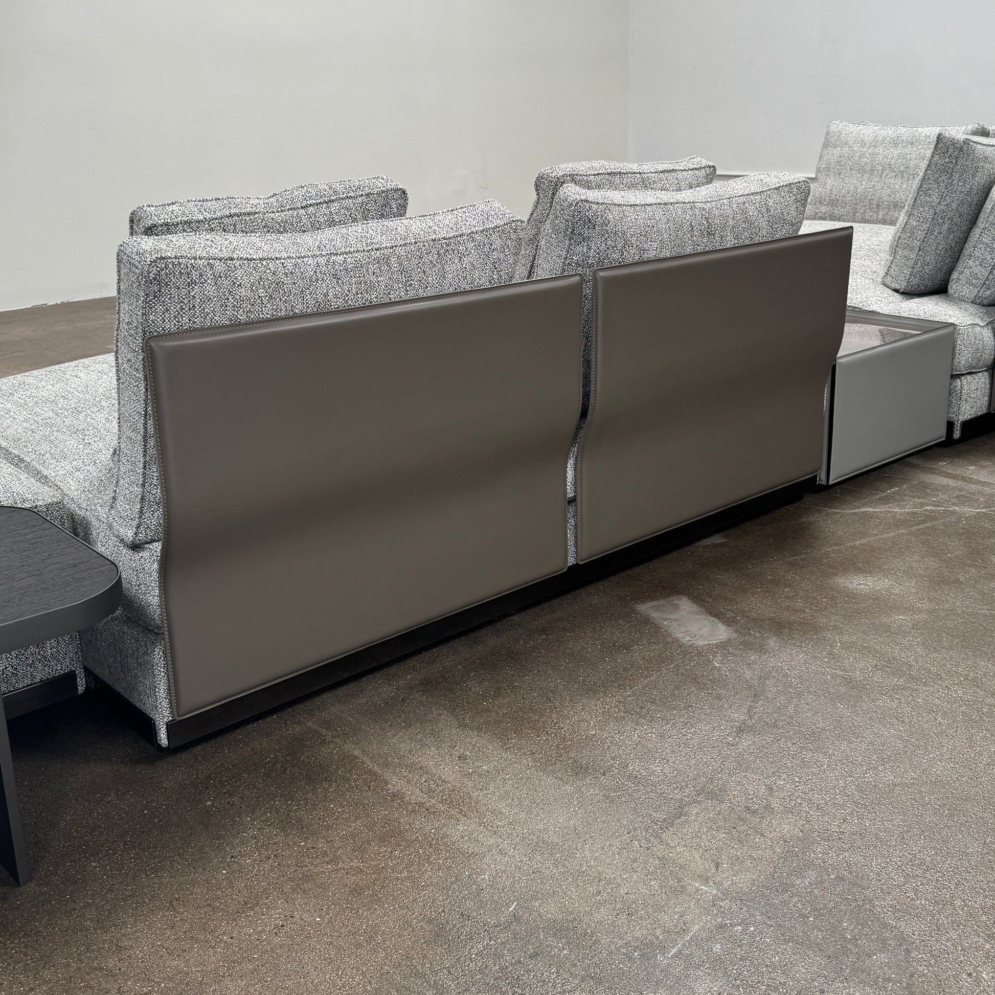 The Minotti West Sectional Sofa with Side Table and Clive Bench by Minotti features a large, L-shaped modern design with gray upholstery, multiple plush cushions, and an integrated side table—perfect for elevating luxury living rooms—all set against a plain white background.