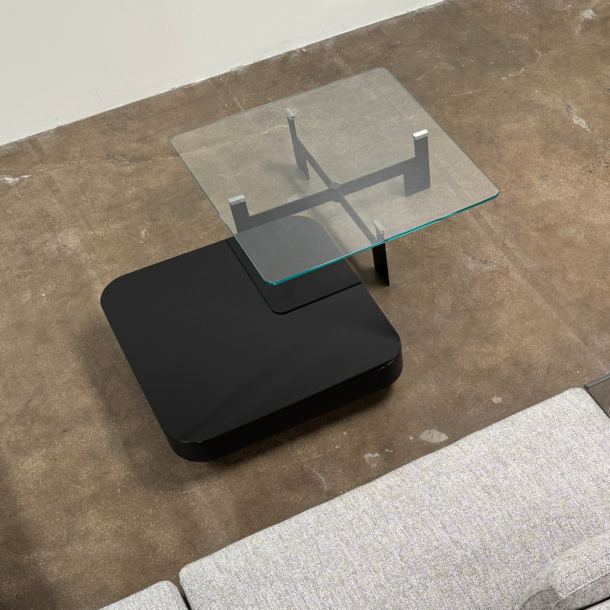 The Minotti Milton + Ellis Coffee Table Set by Minotti features a contemporary design with a black rectangular base and an attached elevated glass top supported by sleek metal brackets, presented against a plain white background.