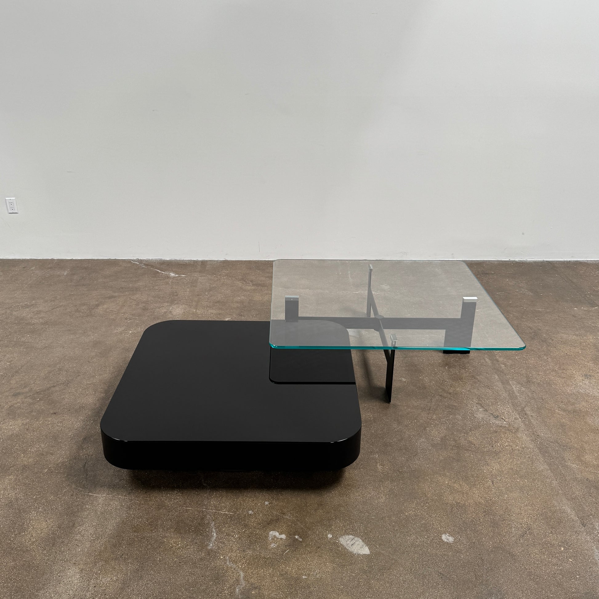 The Minotti Milton + Ellis Coffee Table Set by Minotti features a contemporary design with a black rectangular base and an attached elevated glass top supported by sleek metal brackets, presented against a plain white background.
