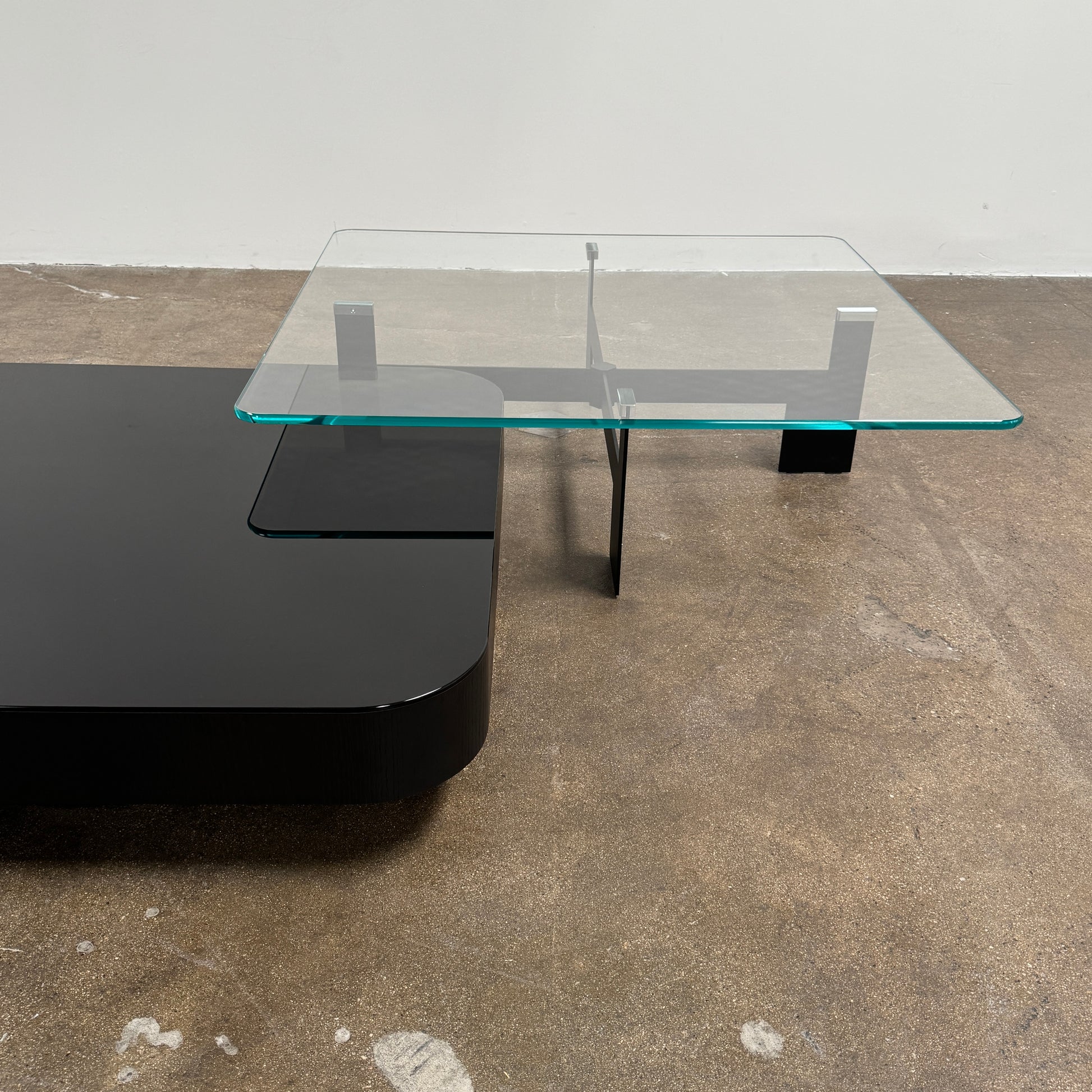 The Minotti Milton + Ellis Coffee Table Set by Minotti features a contemporary design with a black rectangular base and an attached elevated glass top supported by sleek metal brackets, presented against a plain white background.