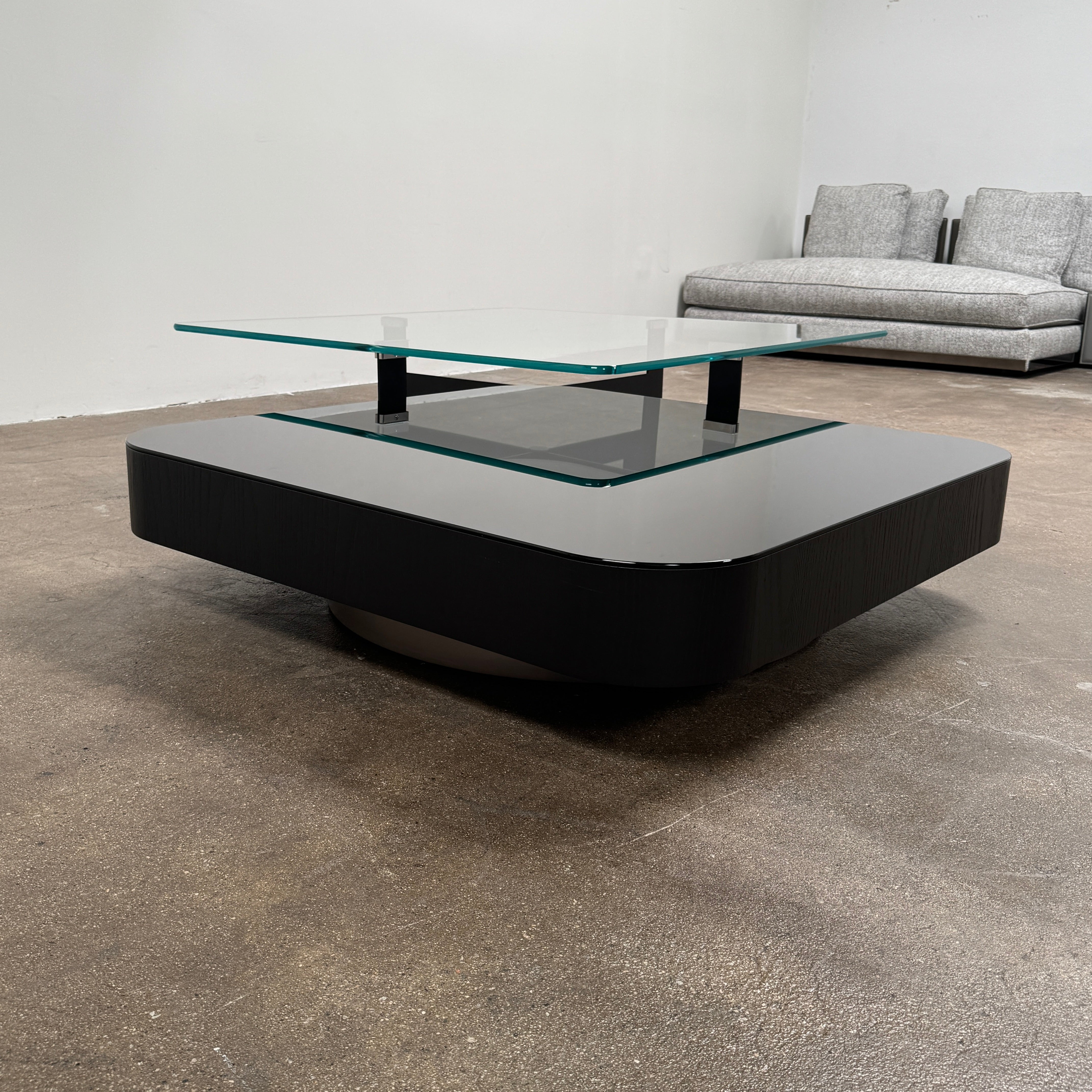 The Minotti Milton + Ellis Coffee Table Set by Minotti features a contemporary design with a black rectangular base and an attached elevated glass top supported by sleek metal brackets, presented against a plain white background.