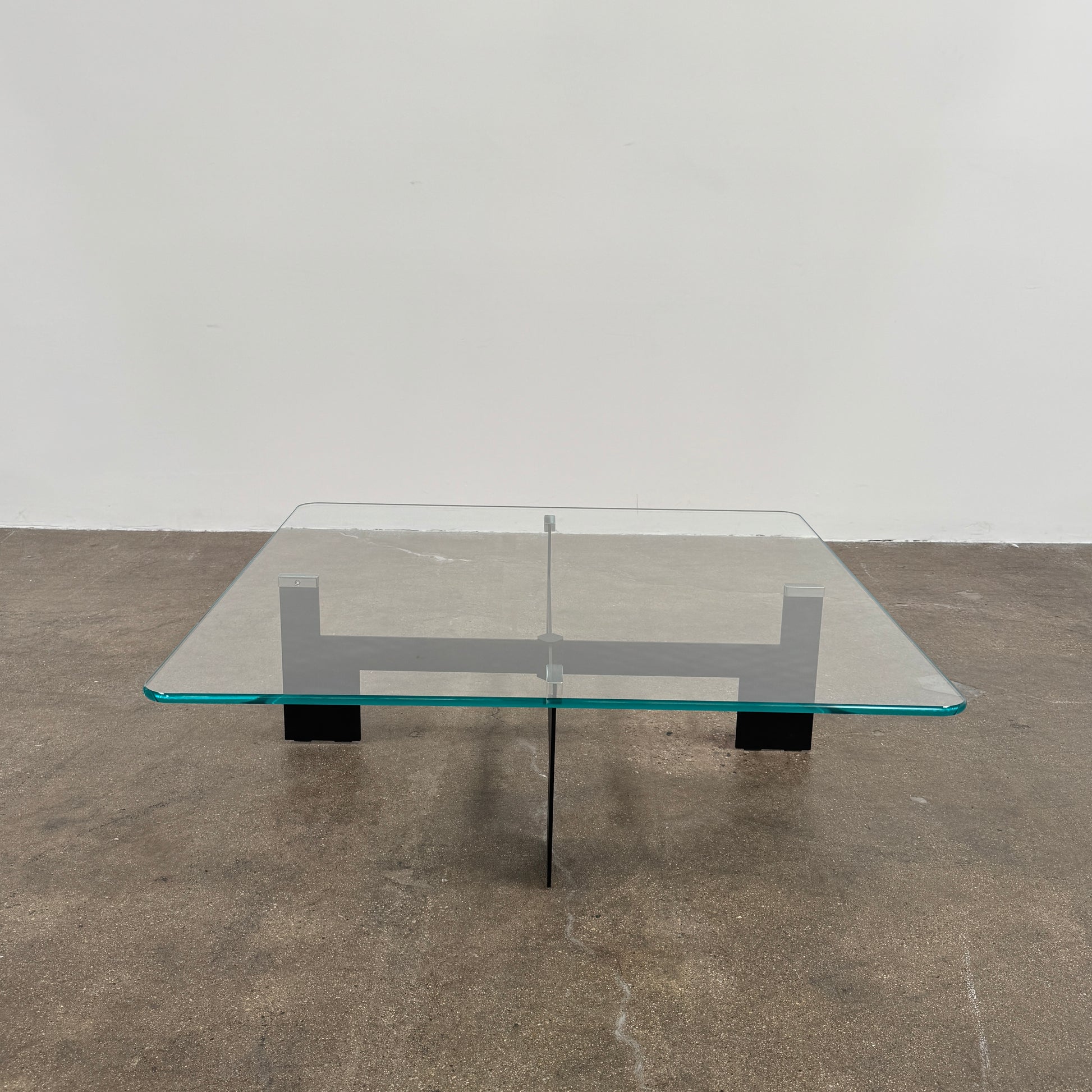 The Minotti Milton + Ellis Coffee Table Set by Minotti features a contemporary design with a black rectangular base and an attached elevated glass top supported by sleek metal brackets, presented against a plain white background.