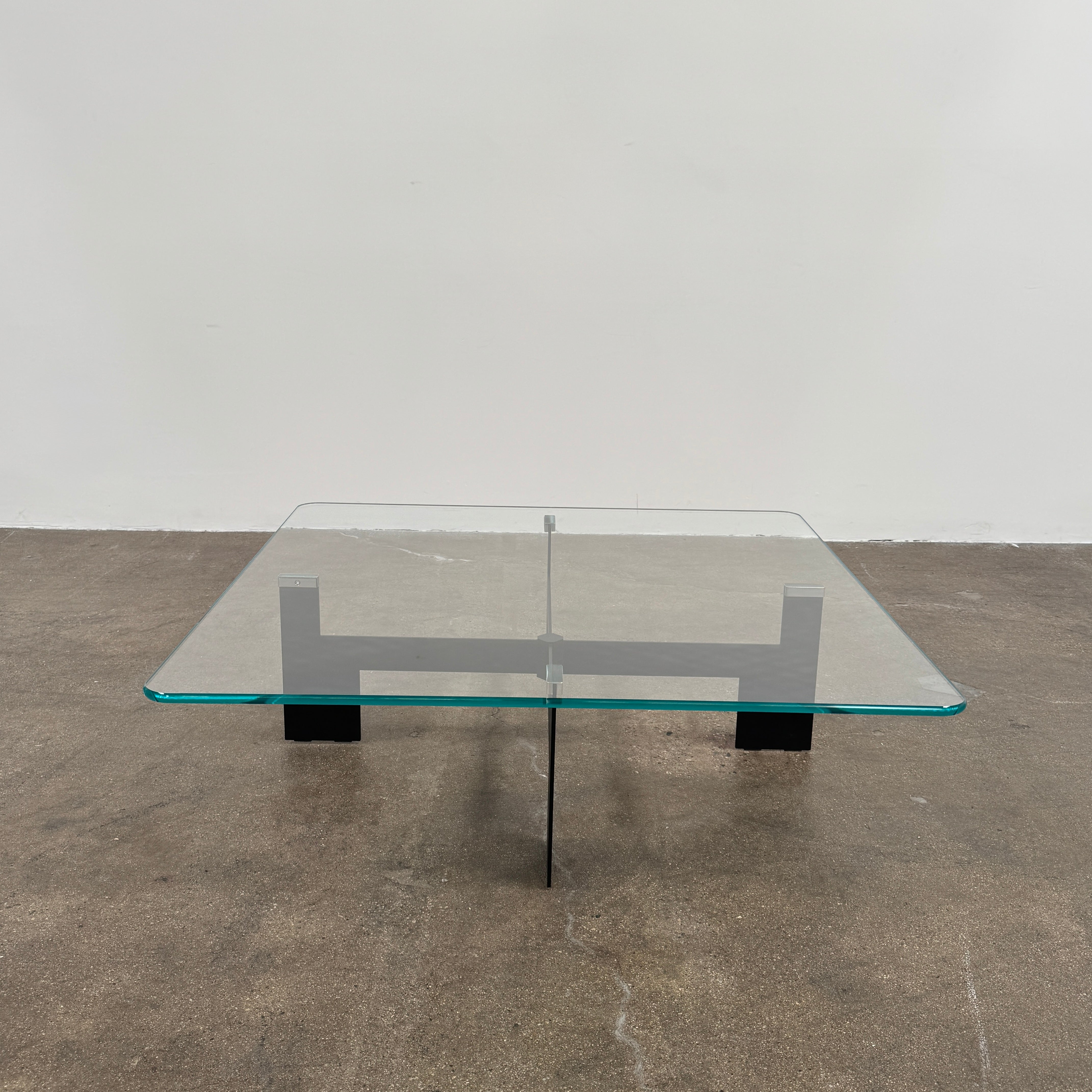 The Minotti Milton + Ellis Coffee Table Set by Minotti features a contemporary design with a black rectangular base and an attached elevated glass top supported by sleek metal brackets, presented against a plain white background.