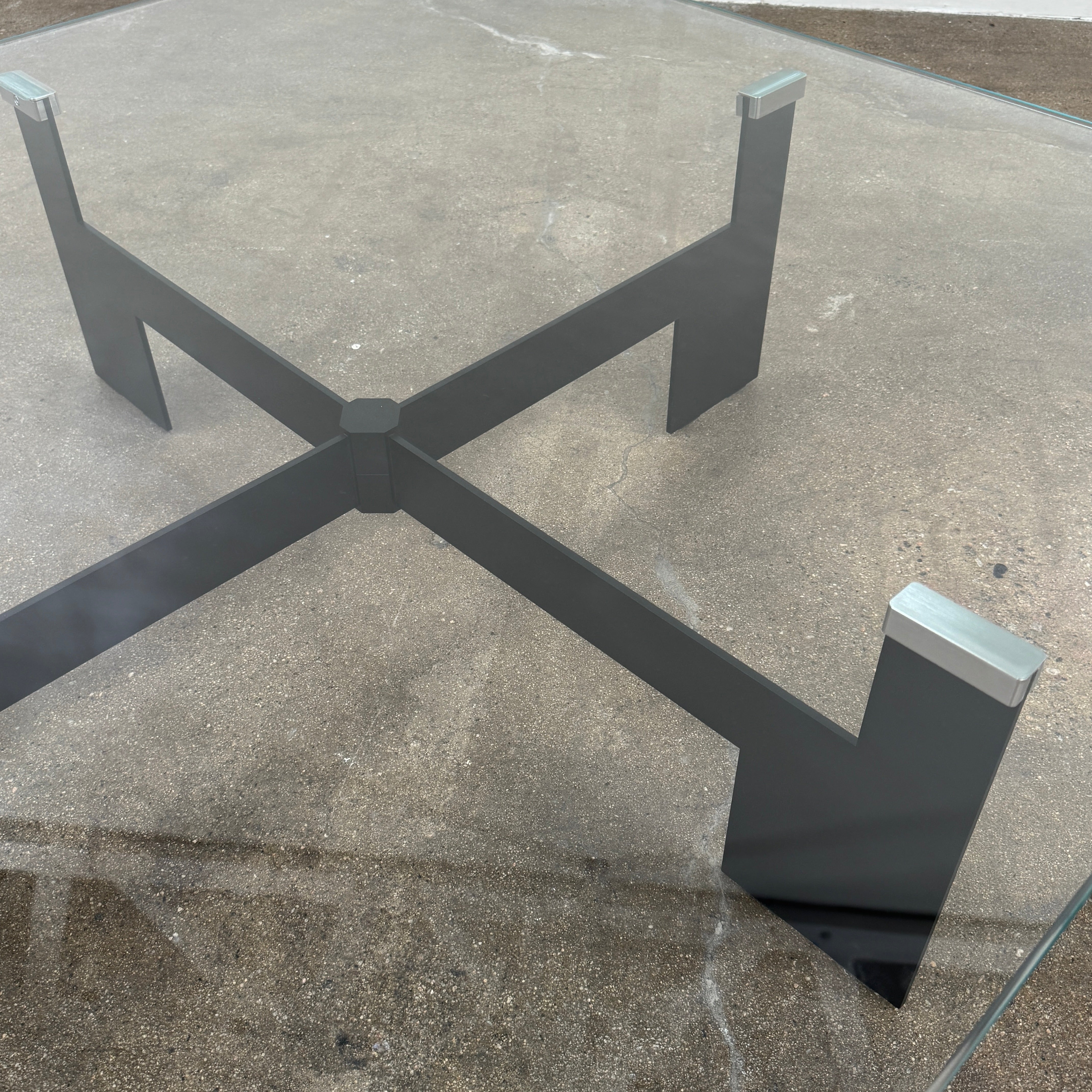 The Minotti Milton + Ellis Coffee Table Set by Minotti features a contemporary design with a black rectangular base and an attached elevated glass top supported by sleek metal brackets, presented against a plain white background.