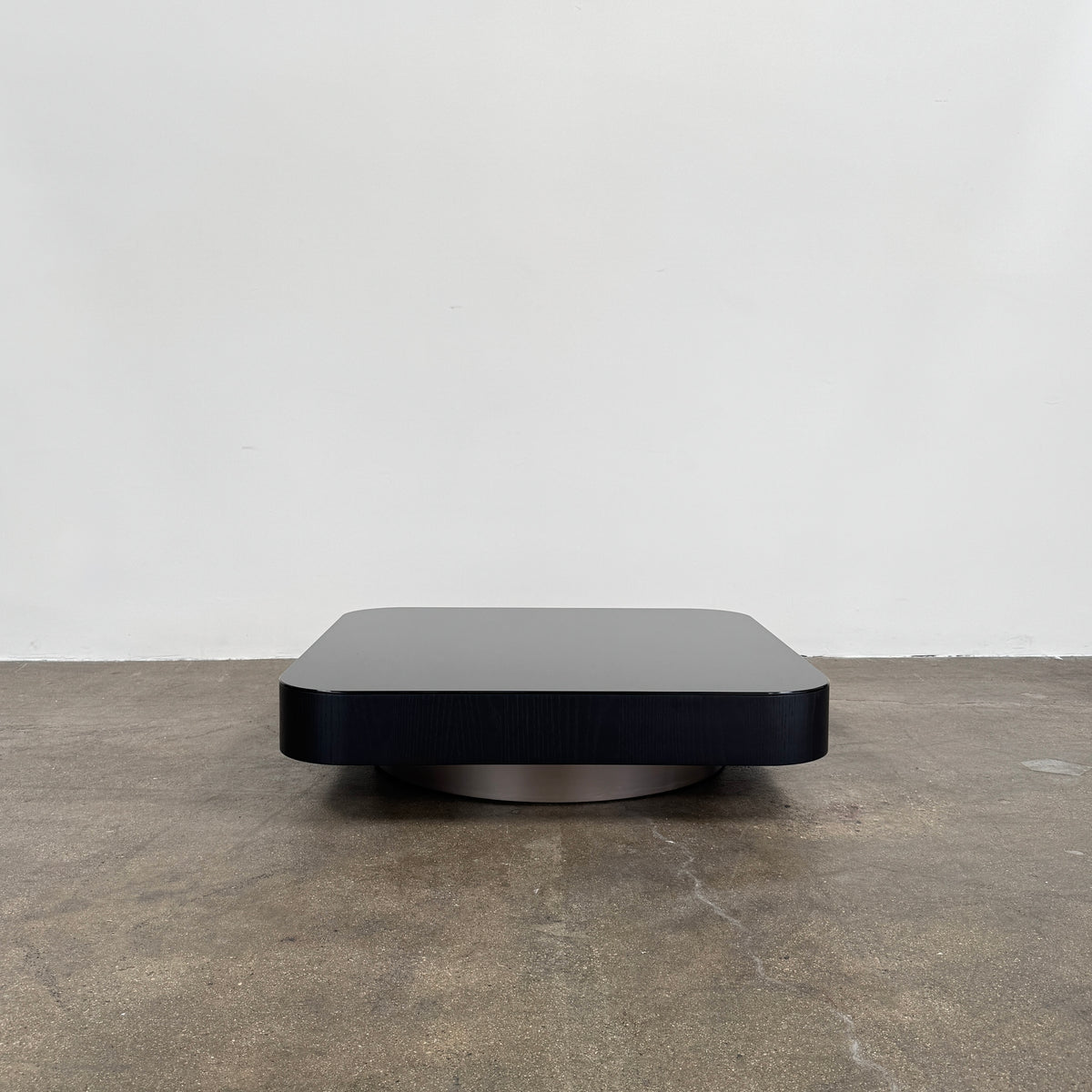 The Minotti Milton Coffee Table by Minotti, featuring a low, square silhouette with rounded corners and a flat surface, stands against a plain white background and embodies contemporary design with an understated sculptural elegance.