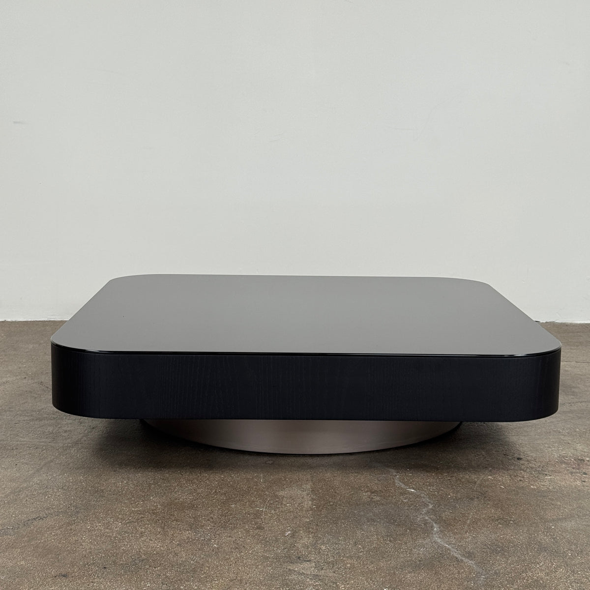 The Minotti Milton Coffee Table by Minotti, featuring a low, square silhouette with rounded corners and a flat surface, stands against a plain white background and embodies contemporary design with an understated sculptural elegance.