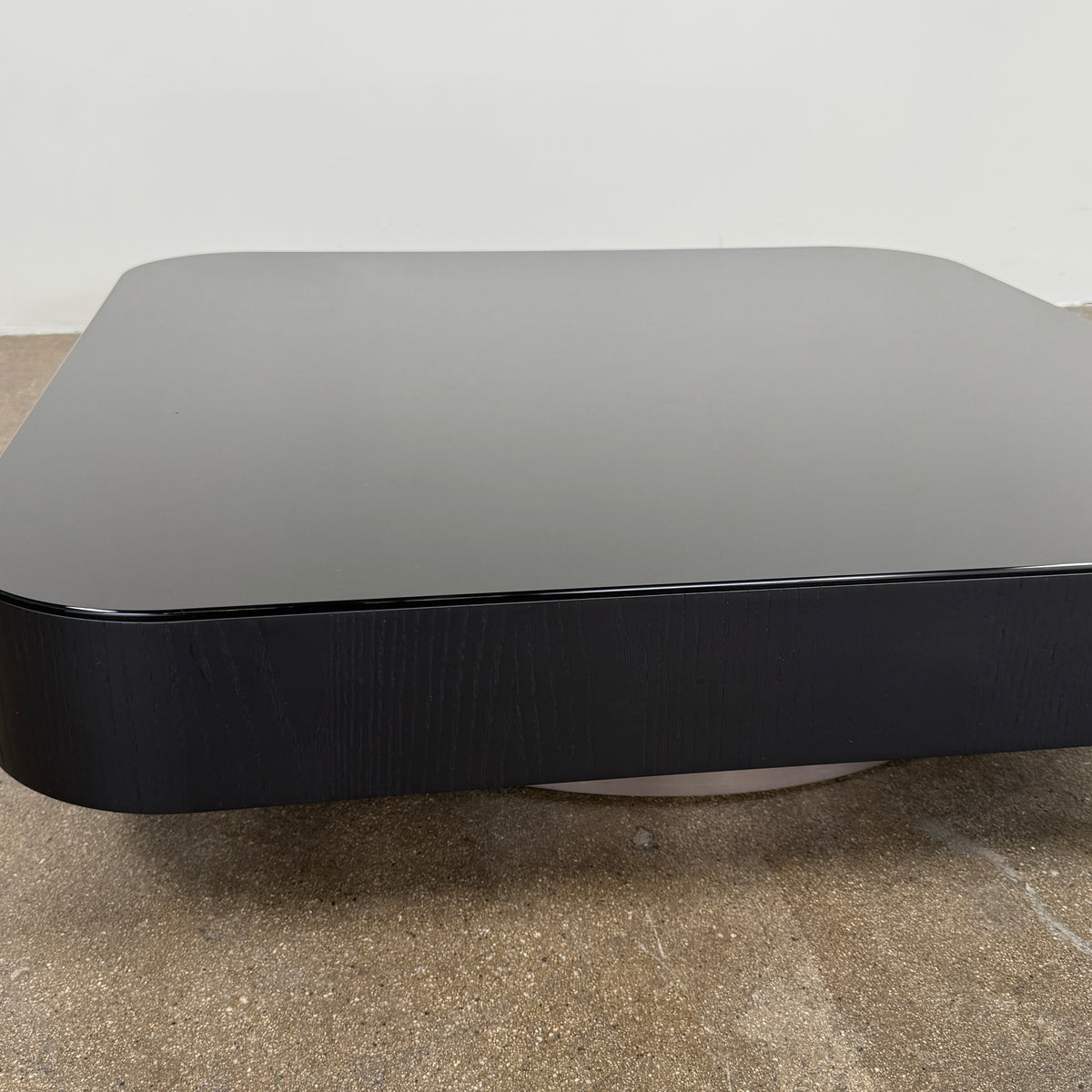The Minotti Milton Coffee Table by Minotti, featuring a low, square silhouette with rounded corners and a flat surface, stands against a plain white background and embodies contemporary design with an understated sculptural elegance.