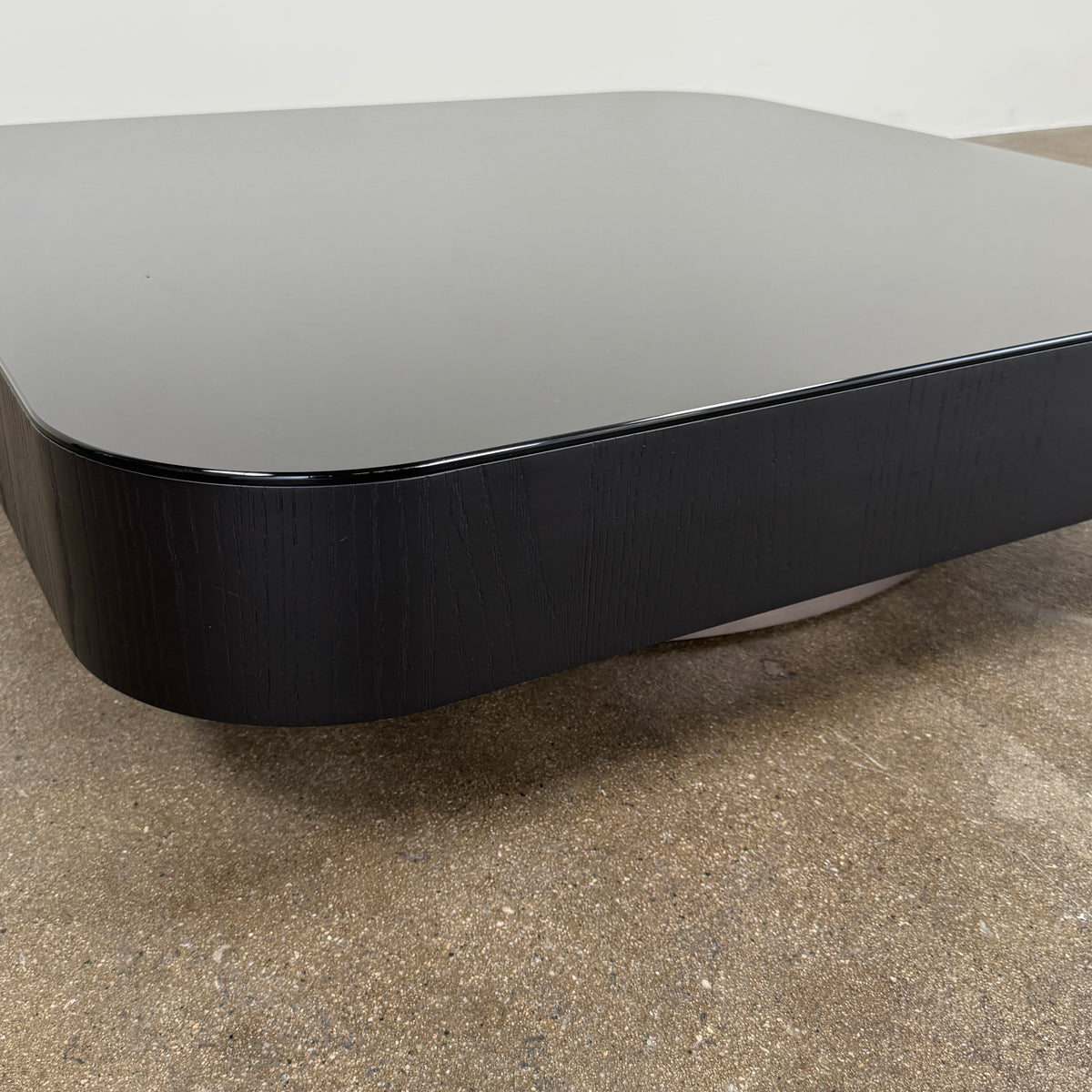 The Minotti Milton Coffee Table by Minotti, featuring a low, square silhouette with rounded corners and a flat surface, stands against a plain white background and embodies contemporary design with an understated sculptural elegance.