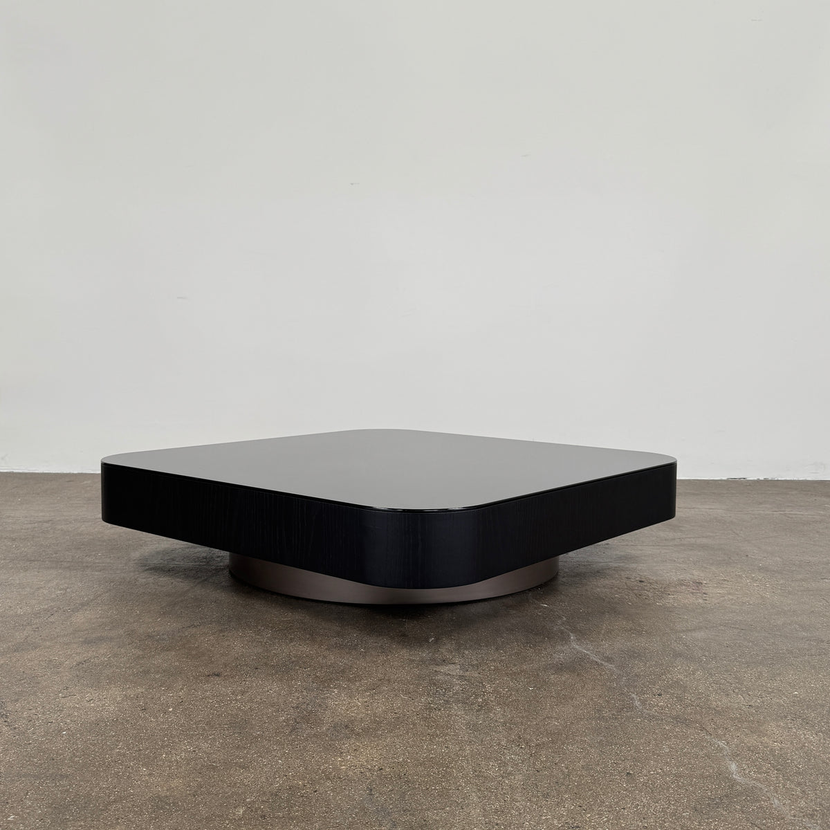 The Minotti Milton Coffee Table by Minotti, featuring a low, square silhouette with rounded corners and a flat surface, stands against a plain white background and embodies contemporary design with an understated sculptural elegance.