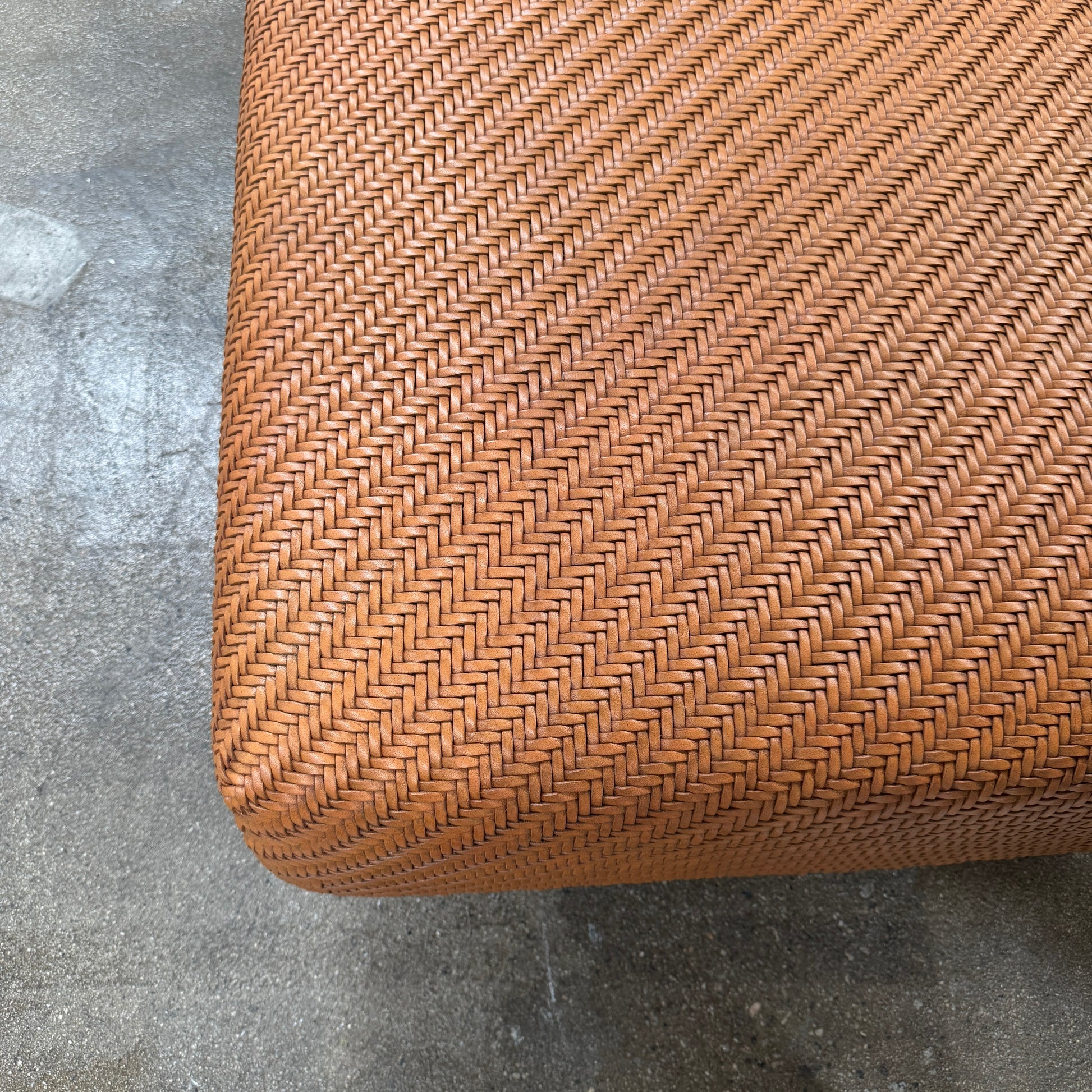 Flexform Filicudi Woven Pouf by Flexform, a rectangular orange bench with a low backless design and metal legs, displayed against a plain white background. Inspired by the iconic Filicudi collection, this elegant piece showcases a distinctive herringbone weave that adds texture and sophistication.