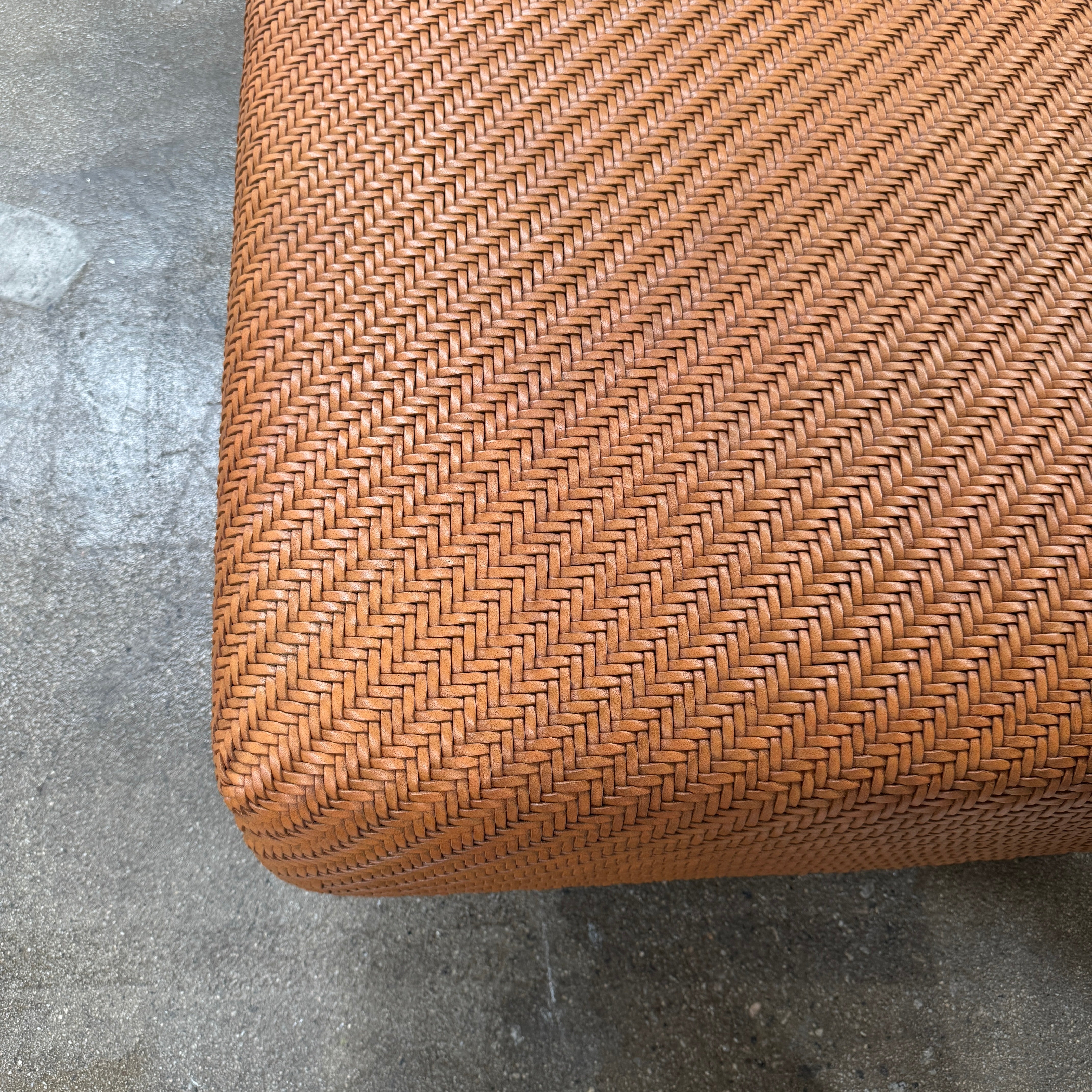 Flexform Filicudi Woven Pouf by Flexform, a rectangular orange bench with a low backless design and metal legs, displayed against a plain white background. Inspired by the iconic Filicudi collection, this elegant piece showcases a distinctive herringbone weave that adds texture and sophistication.
