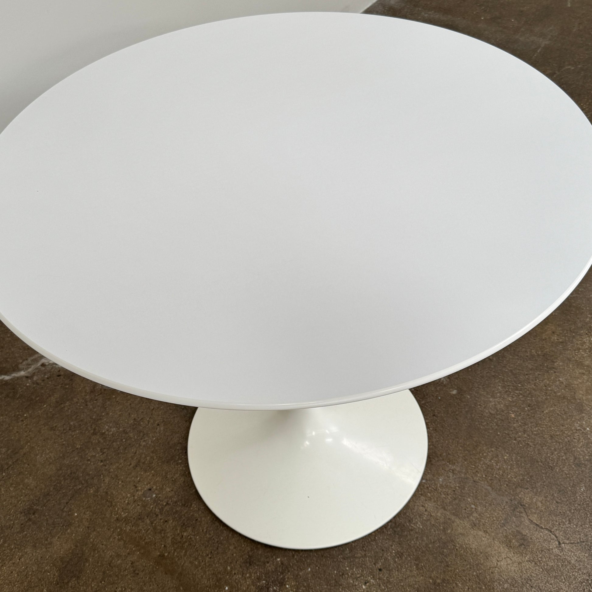 The Knoll Saarinen Dining Table 35" Round by Knoll, featuring a sleek white finish and iconic single pedestal base inspired by the classic Tulip design, is displayed against a plain white background.