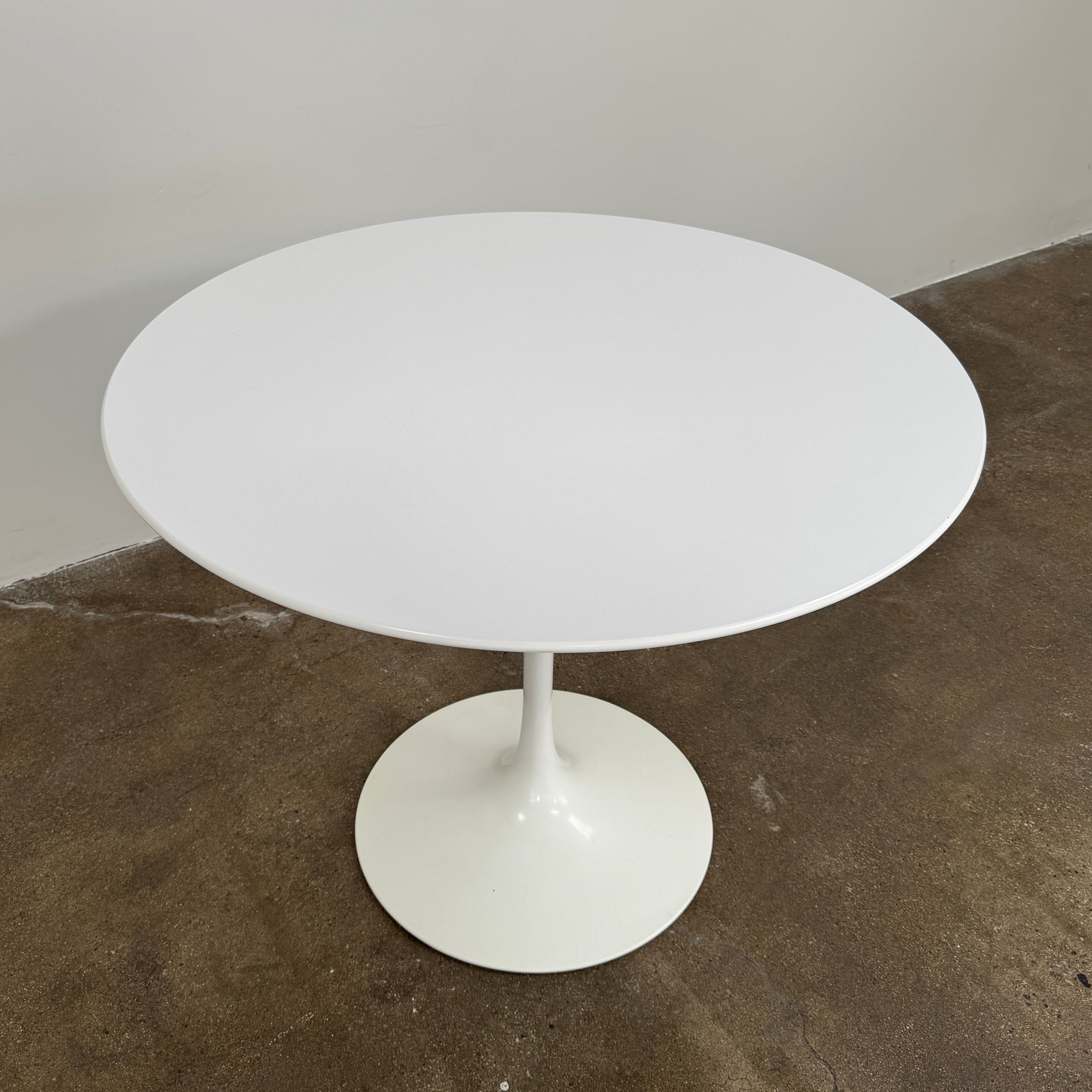 The Knoll Saarinen Dining Table 35" Round by Knoll, featuring a sleek white finish and iconic single pedestal base inspired by the classic Tulip design, is displayed against a plain white background.