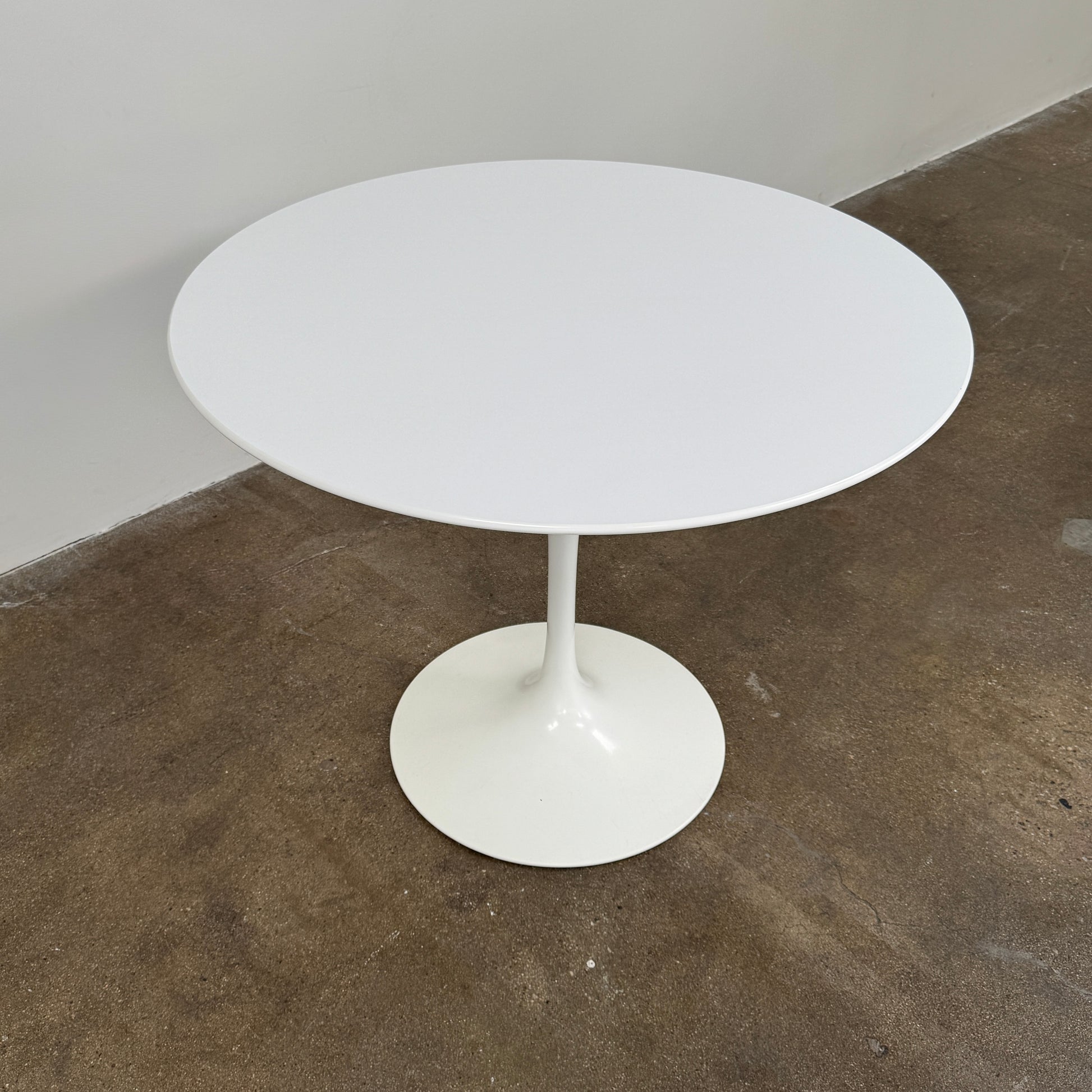 The Knoll Saarinen Dining Table 35" Round by Knoll, featuring a sleek white finish and iconic single pedestal base inspired by the classic Tulip design, is displayed against a plain white background.