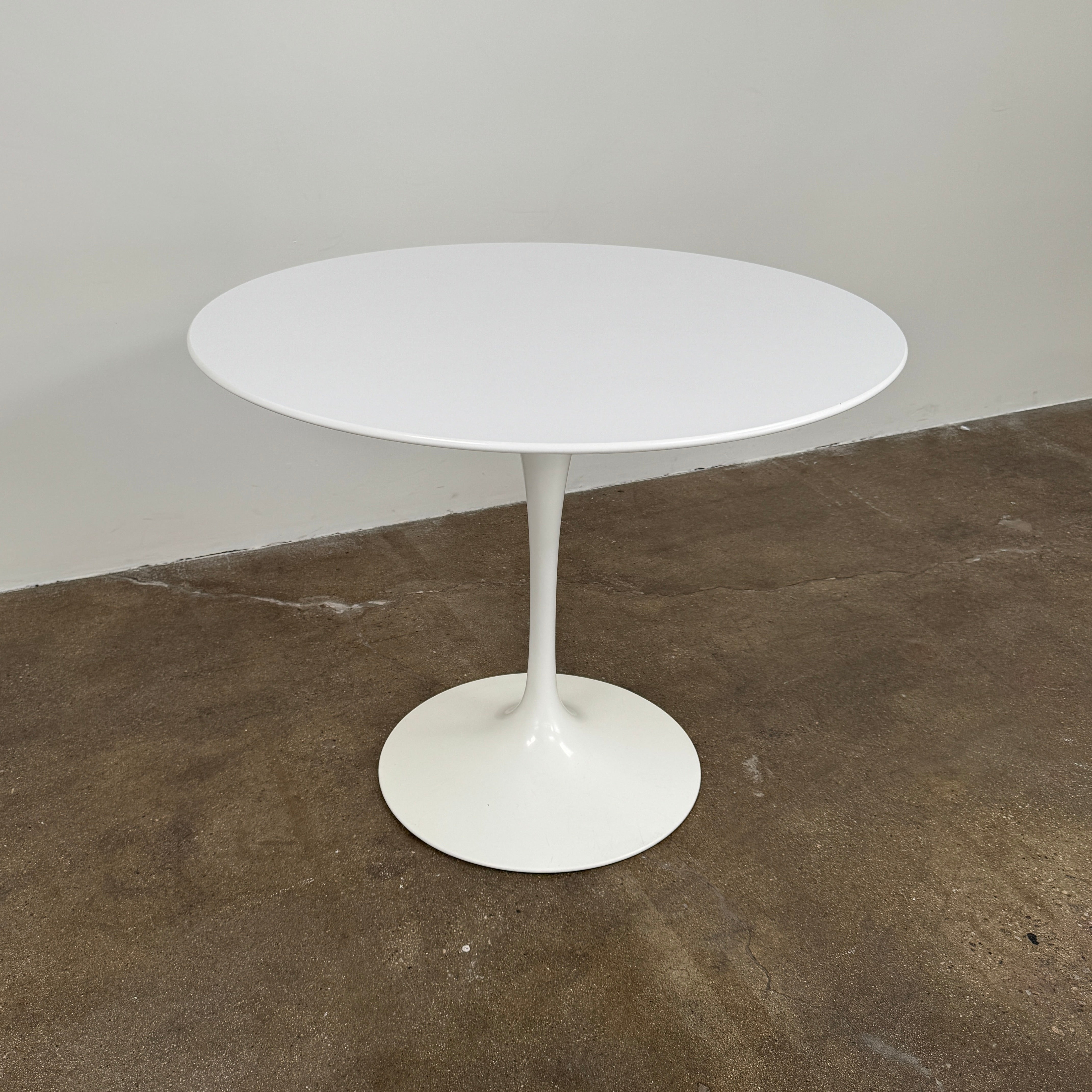 The Knoll Saarinen Dining Table 35" Round by Knoll, featuring a sleek white finish and iconic single pedestal base inspired by the classic Tulip design, is displayed against a plain white background.