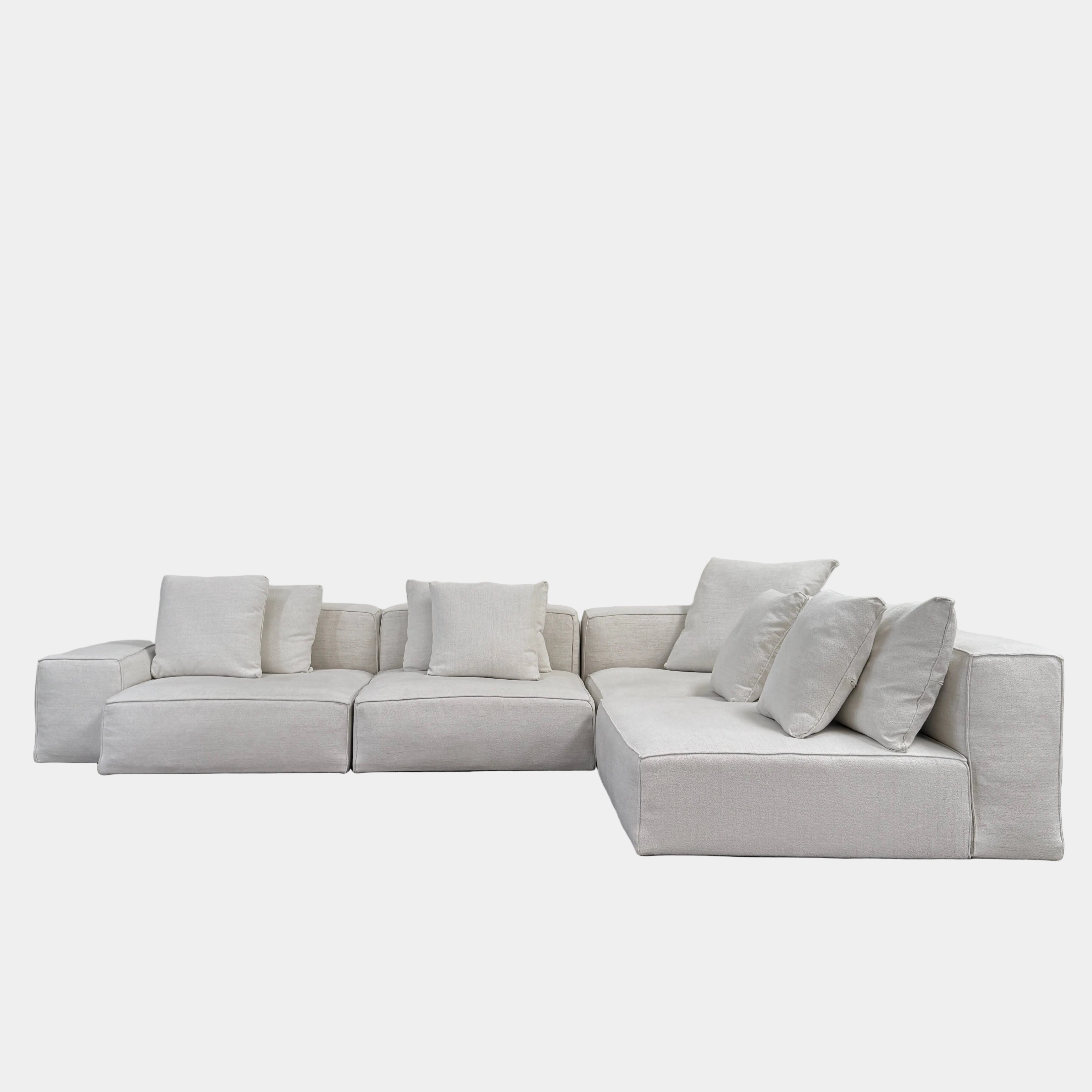 The Living Divani NeoWall 4 piece Modular Sofa by Living Divani is a modern, light beige Italian modular sofa featuring six large seat cushions and seven matching throw pillows, displayed against a white background.