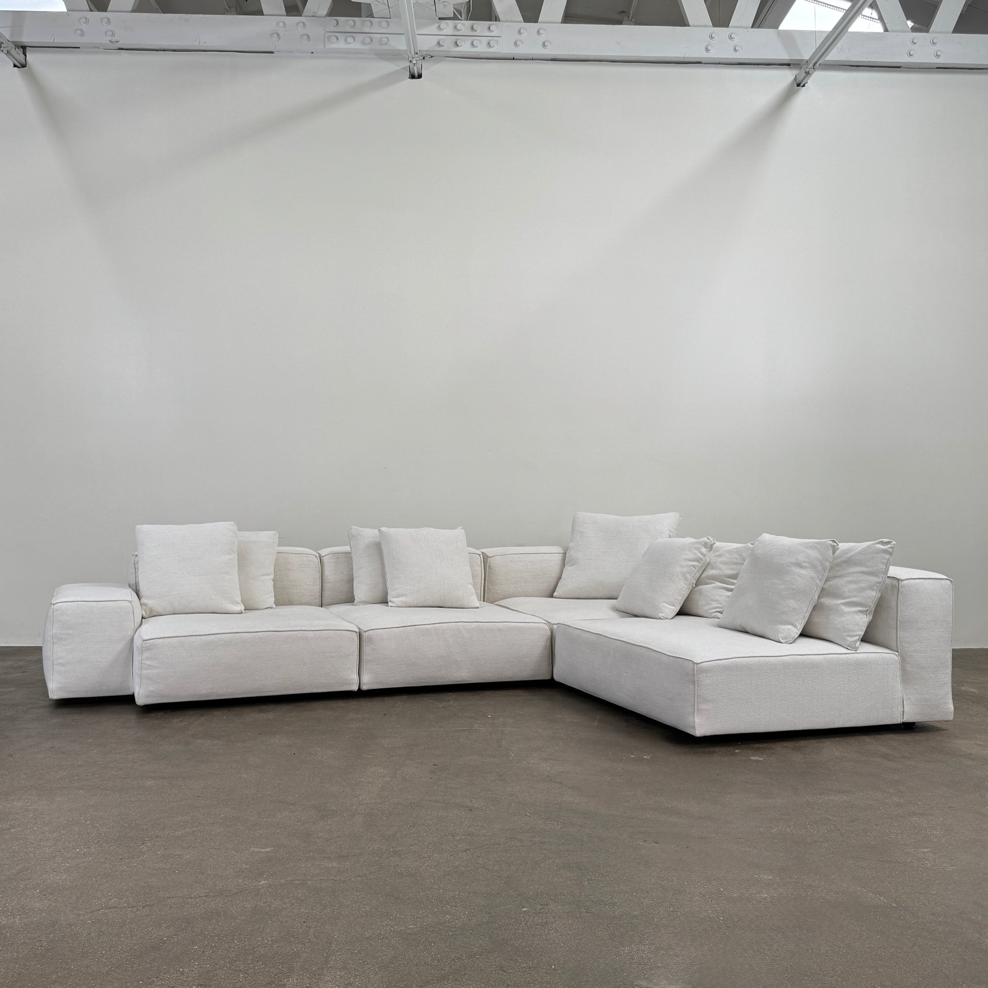 The Living Divani NeoWall 4 piece Modular Sofa by Living Divani is a modern, light beige Italian modular sofa featuring six large seat cushions and seven matching throw pillows, displayed against a white background.