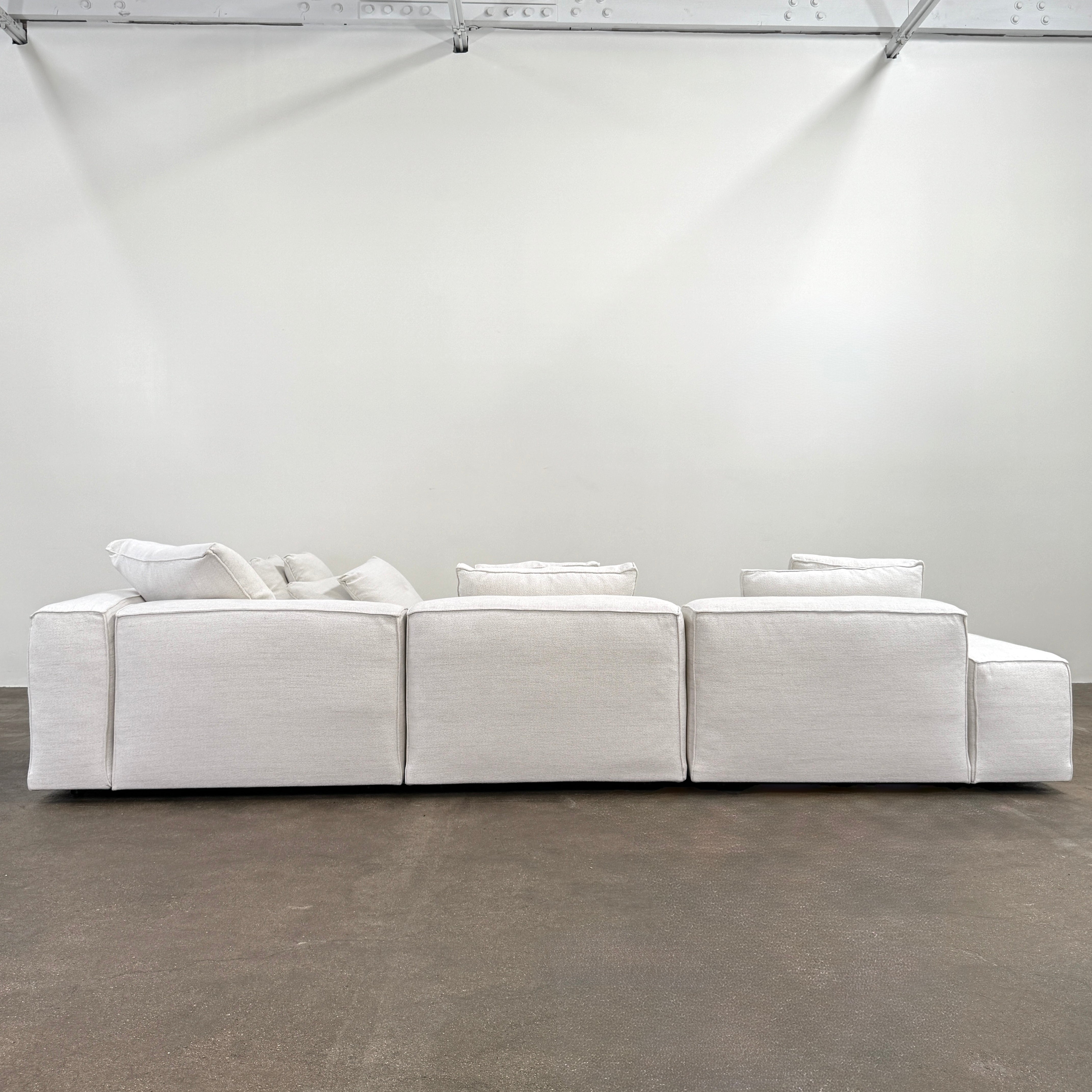 The Living Divani NeoWall 4 piece Modular Sofa by Living Divani is a modern, light beige Italian modular sofa featuring six large seat cushions and seven matching throw pillows, displayed against a white background.