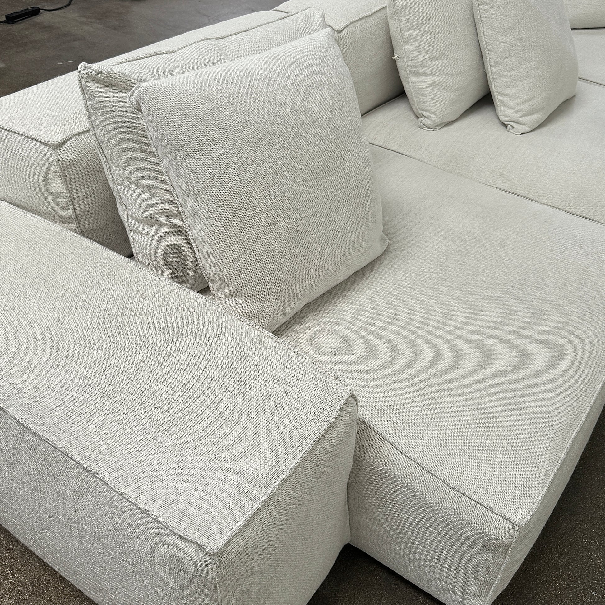 The Living Divani NeoWall 4 piece Modular Sofa by Living Divani is a modern, light beige Italian modular sofa featuring six large seat cushions and seven matching throw pillows, displayed against a white background.