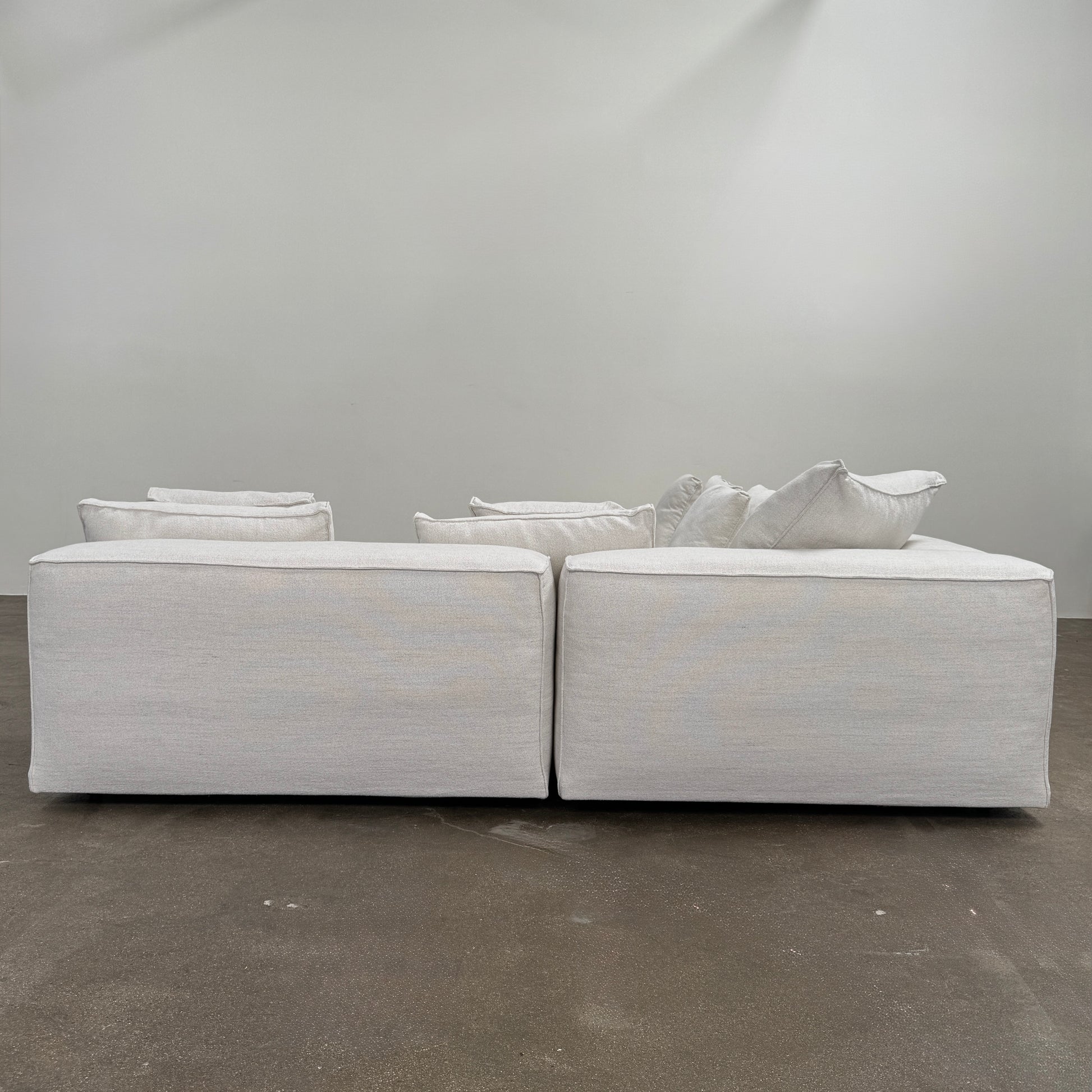 The Living Divani NeoWall 4 piece Modular Sofa by Living Divani is a modern, light beige Italian modular sofa featuring six large seat cushions and seven matching throw pillows, displayed against a white background.