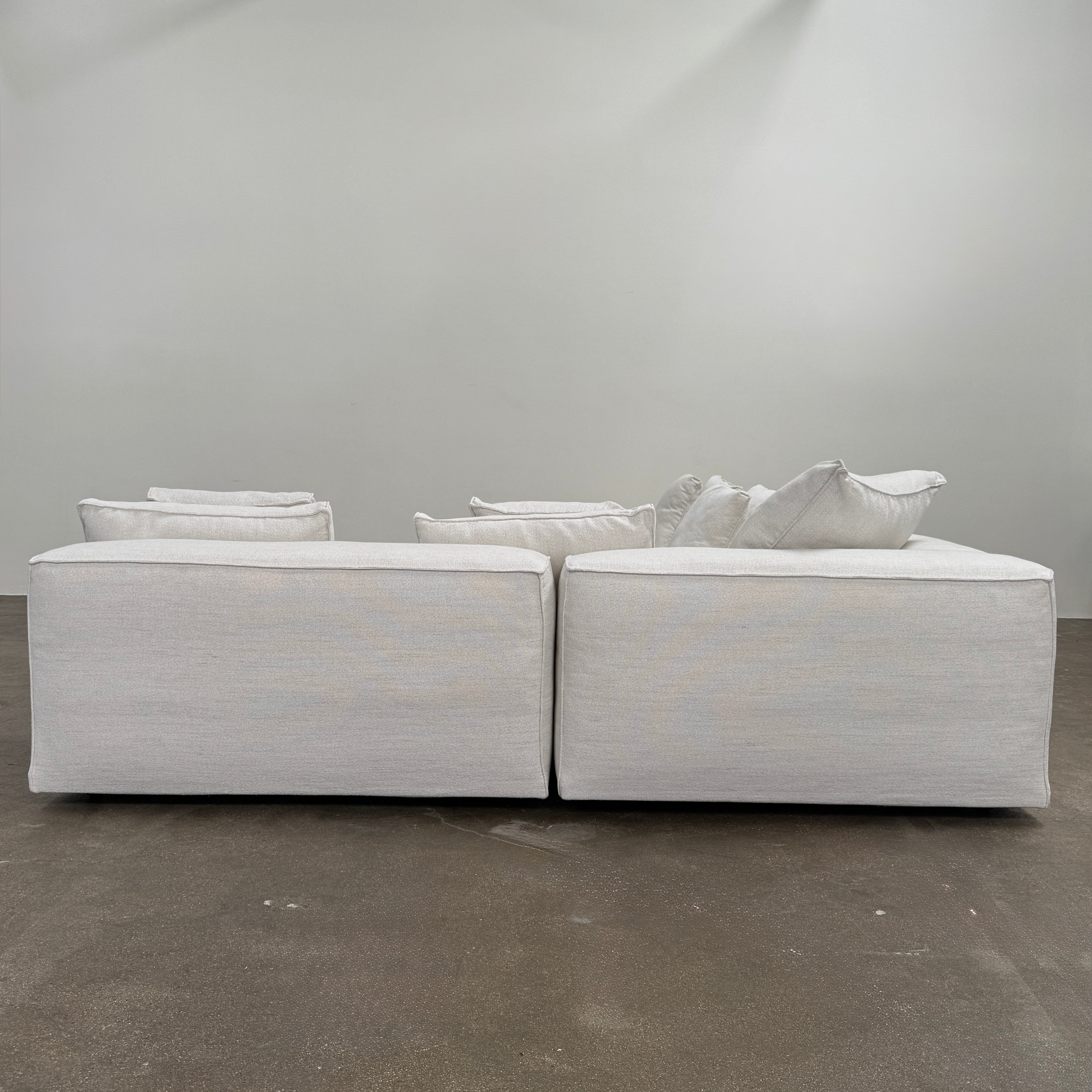 The Living Divani NeoWall 4 piece Modular Sofa by Living Divani is a modern, light beige Italian modular sofa featuring six large seat cushions and seven matching throw pillows, displayed against a white background.