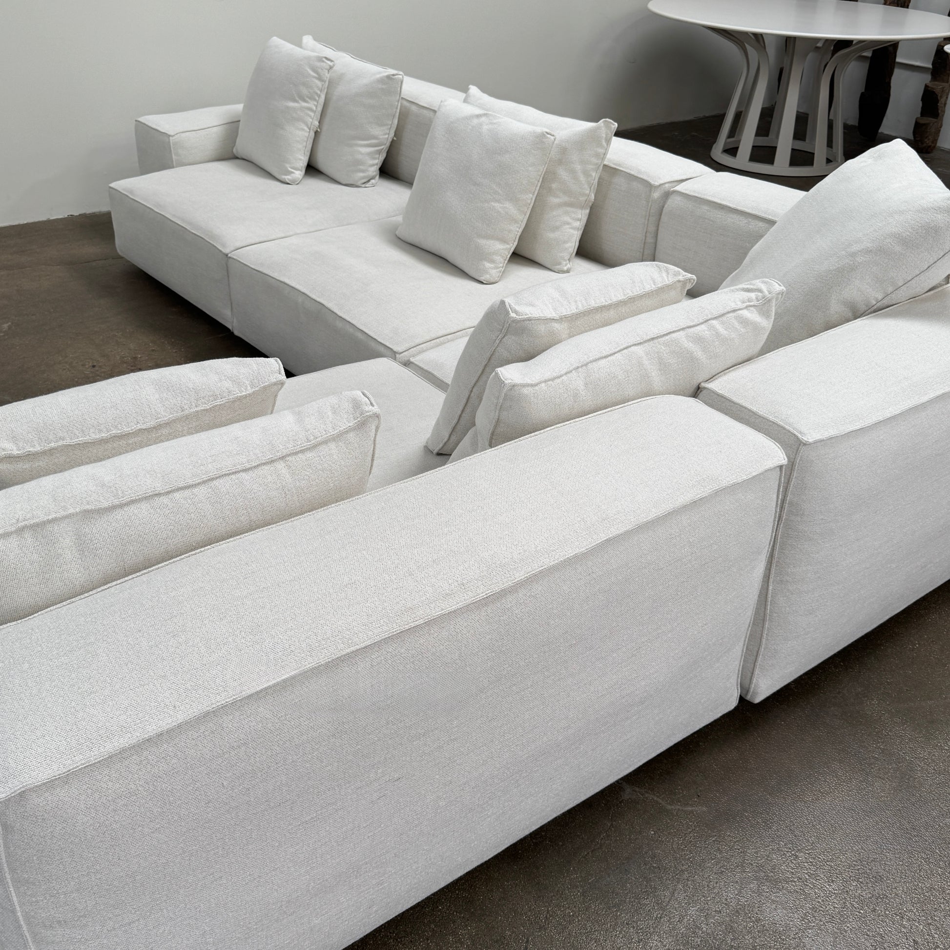 The Living Divani NeoWall 4 piece Modular Sofa by Living Divani is a modern, light beige Italian modular sofa featuring six large seat cushions and seven matching throw pillows, displayed against a white background.