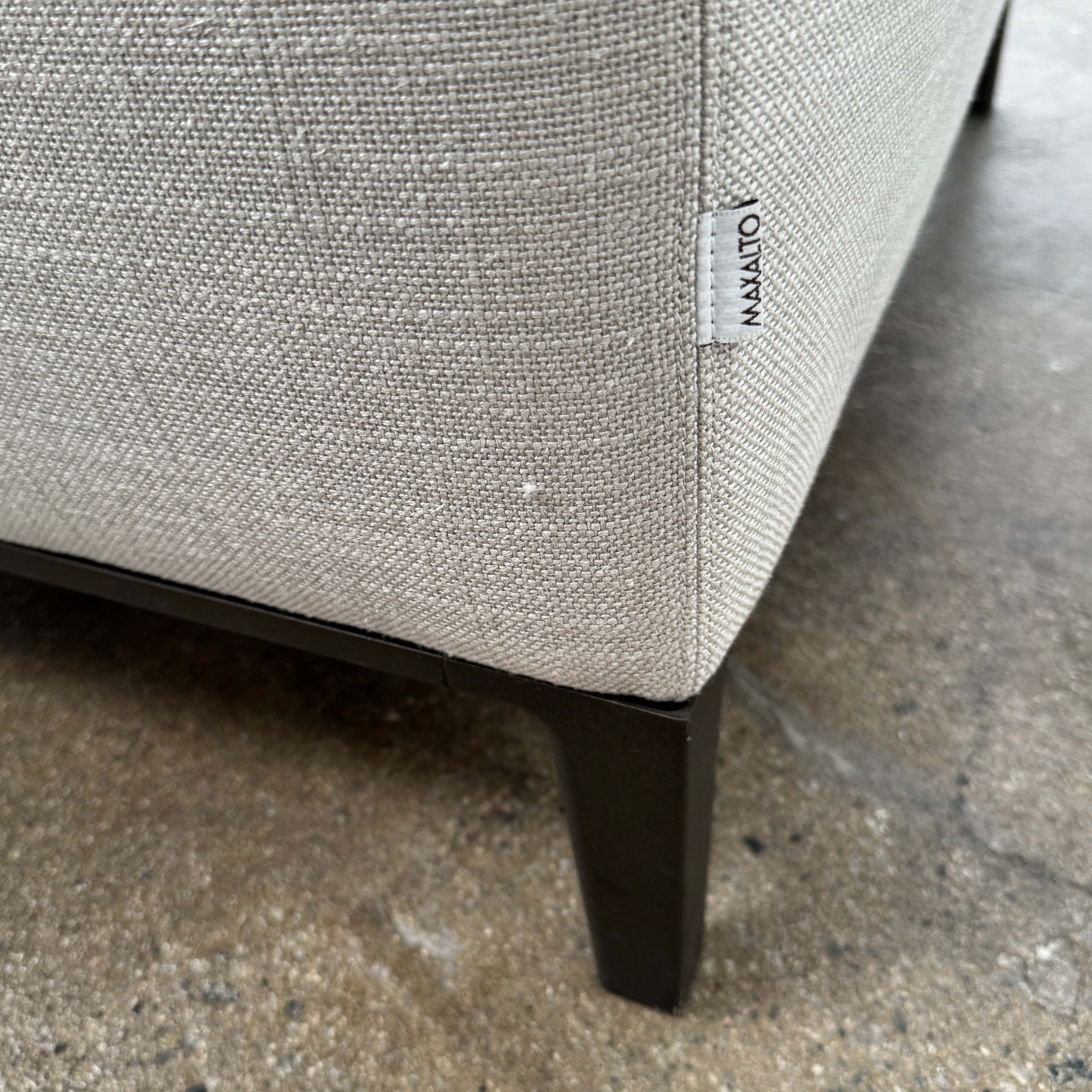 A modern Maxalto Lucrezia Soft Armchair in light gray, featuring square arms, a cushioned seat and back, and dark wooden legs from Maxalto, showcases refined design and plush comfort against a plain white background.
