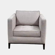 A modern Maxalto Lucrezia Soft Armchair in light gray, featuring square arms, a cushioned seat and back, and dark wooden legs from Maxalto, showcases refined design and plush comfort against a plain white background.