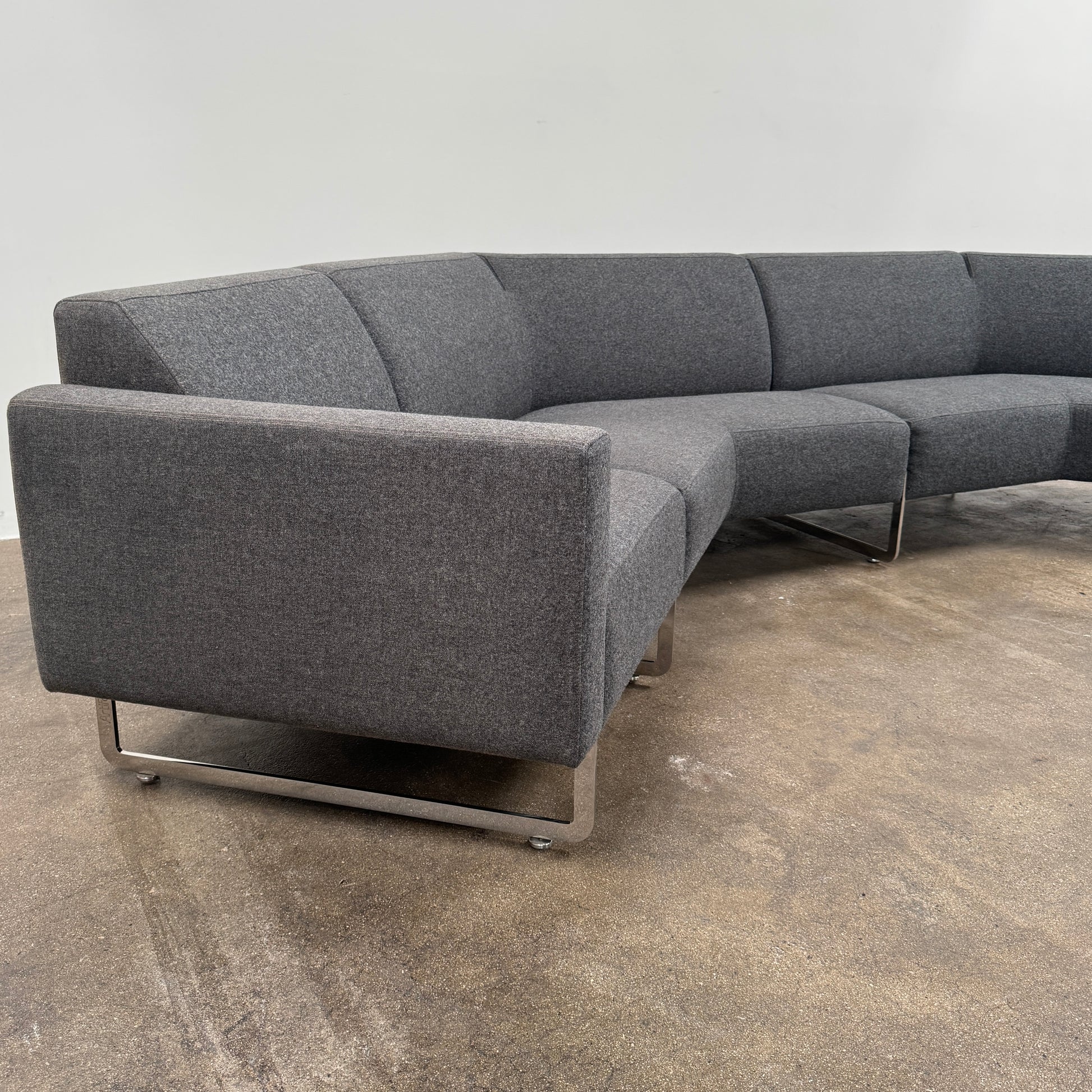The Artifort More Mare Sectional by Artifort is a modern, dark gray sectional sofa featuring a minimalist metal frame and luxurious gray wool upholstery inspired by René Holten’s design, set against a plain white background.