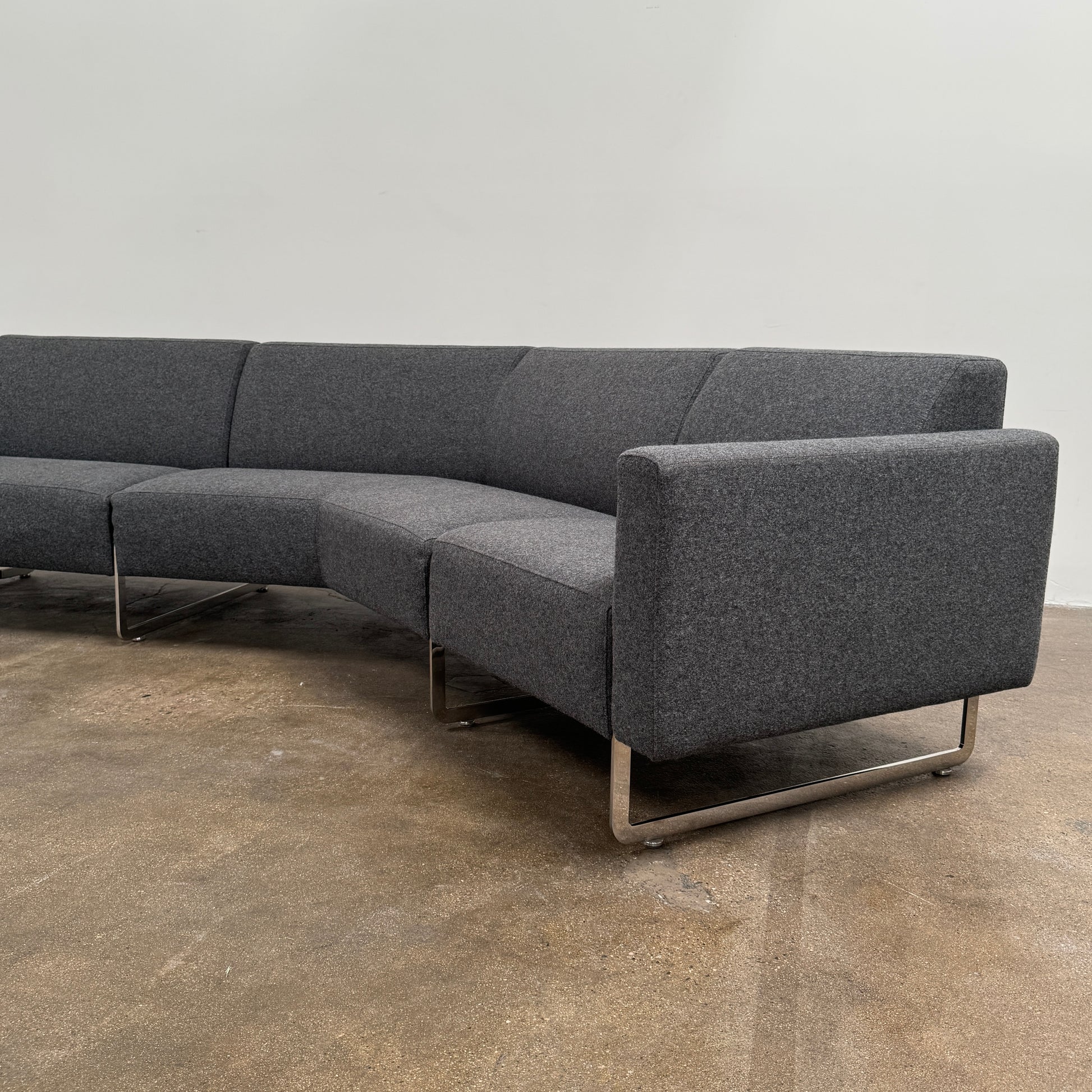 The Artifort More Mare Sectional by Artifort is a modern, dark gray sectional sofa featuring a minimalist metal frame and luxurious gray wool upholstery inspired by René Holten’s design, set against a plain white background.