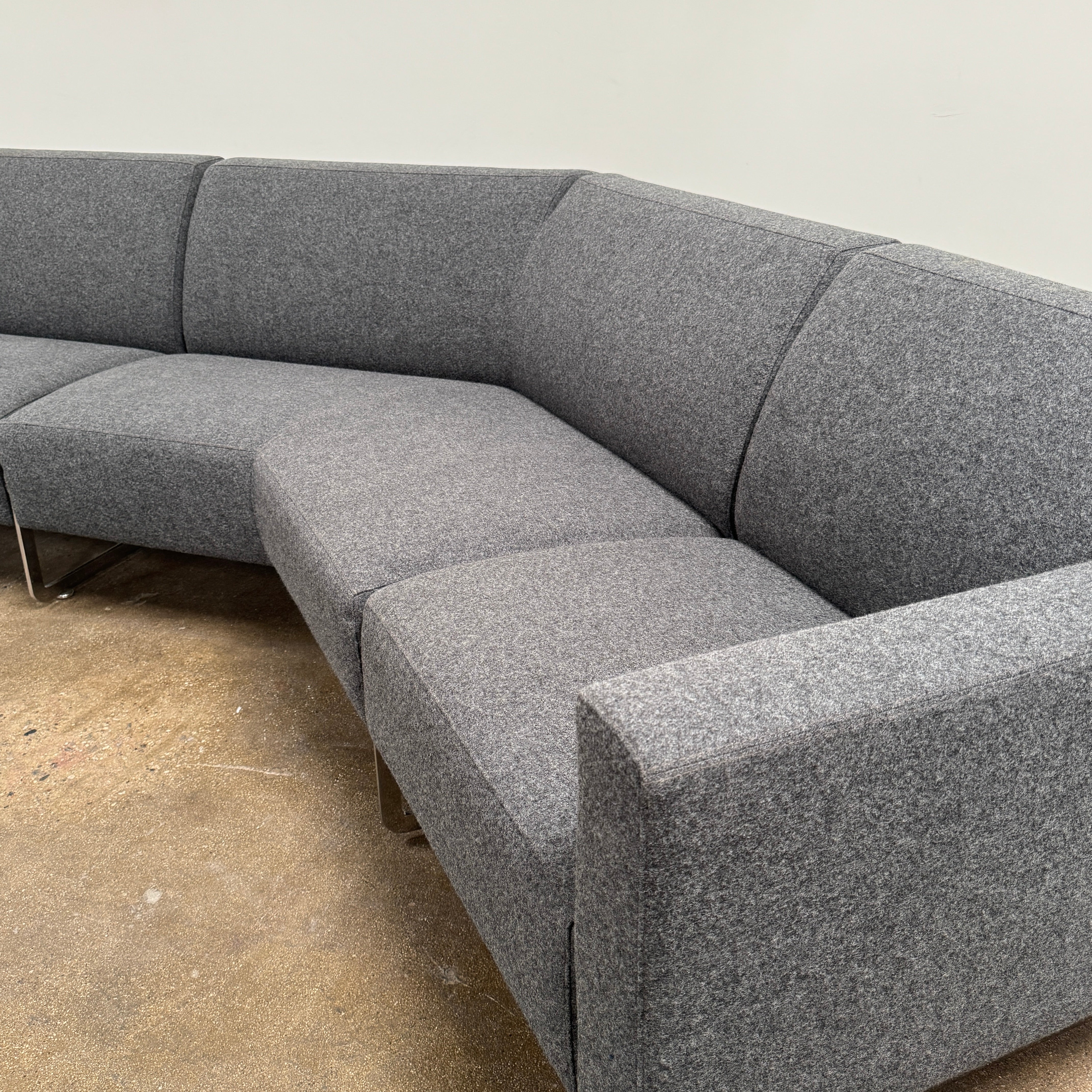 The Artifort More Mare Sectional by Artifort is a modern, dark gray sectional sofa featuring a minimalist metal frame and luxurious gray wool upholstery inspired by René Holten’s design, set against a plain white background.