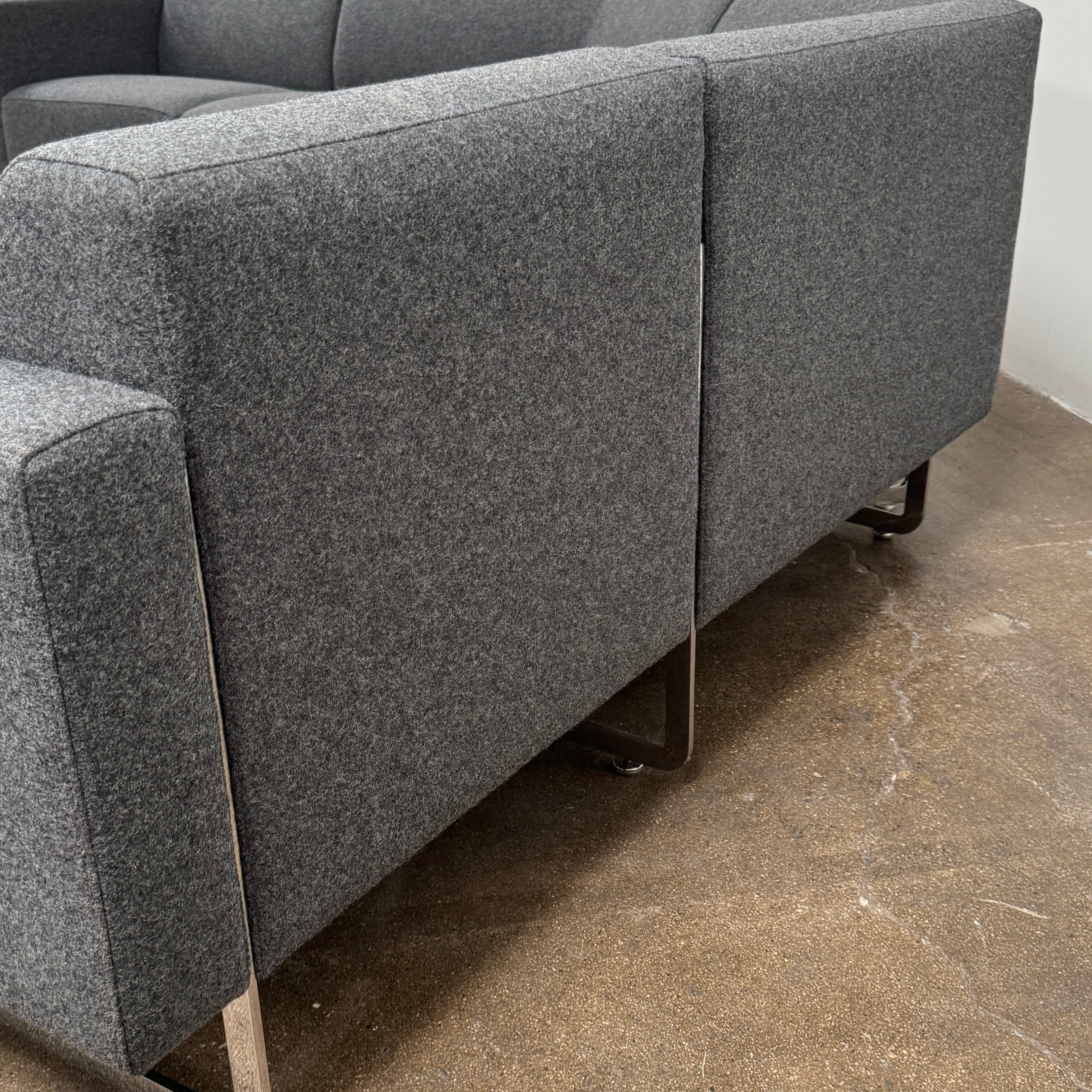 The Artifort More Mare Sectional by Artifort is a modern, dark gray sectional sofa featuring a minimalist metal frame and luxurious gray wool upholstery inspired by René Holten’s design, set against a plain white background.