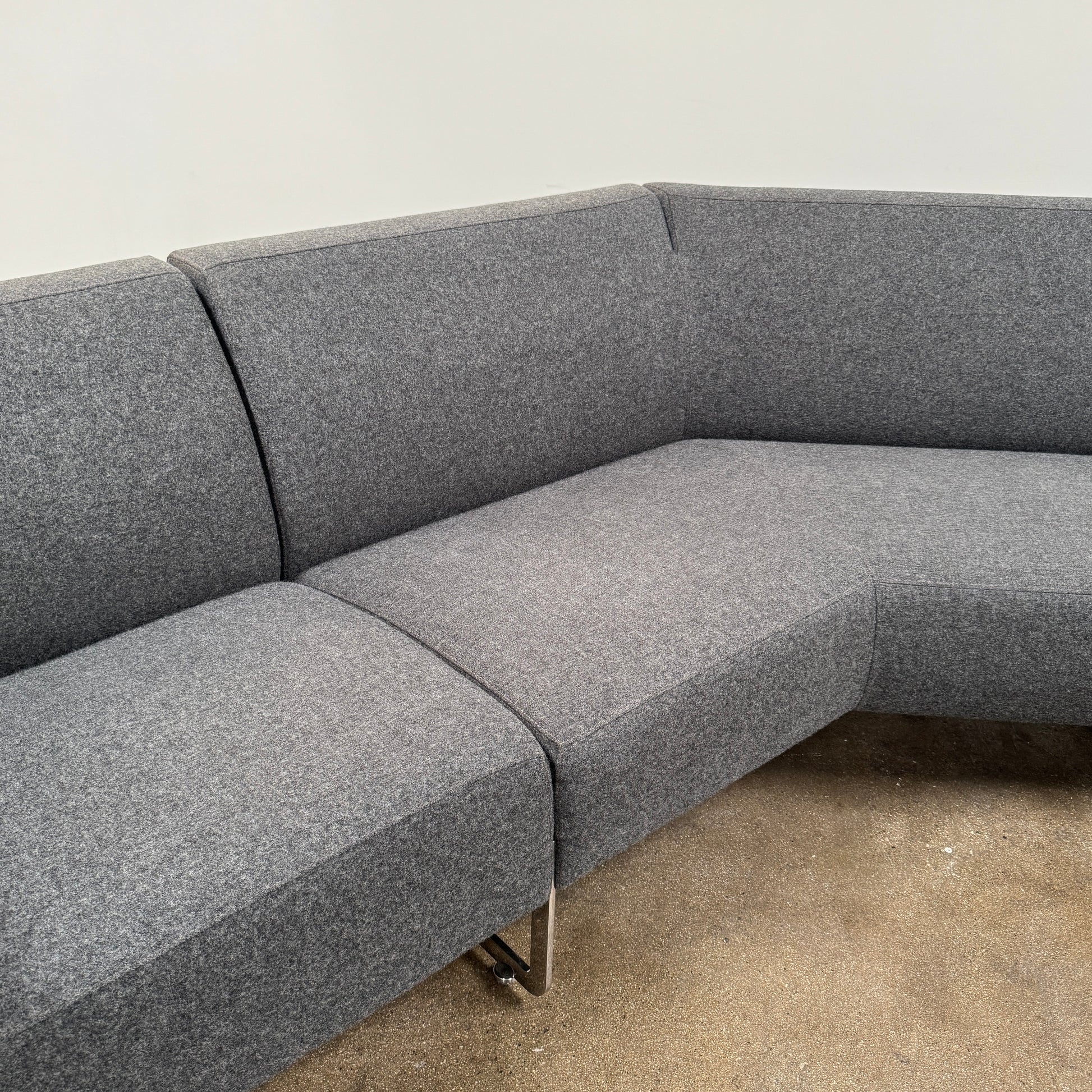 The Artifort More Mare Sectional by Artifort is a modern, dark gray sectional sofa featuring a minimalist metal frame and luxurious gray wool upholstery inspired by René Holten’s design, set against a plain white background.