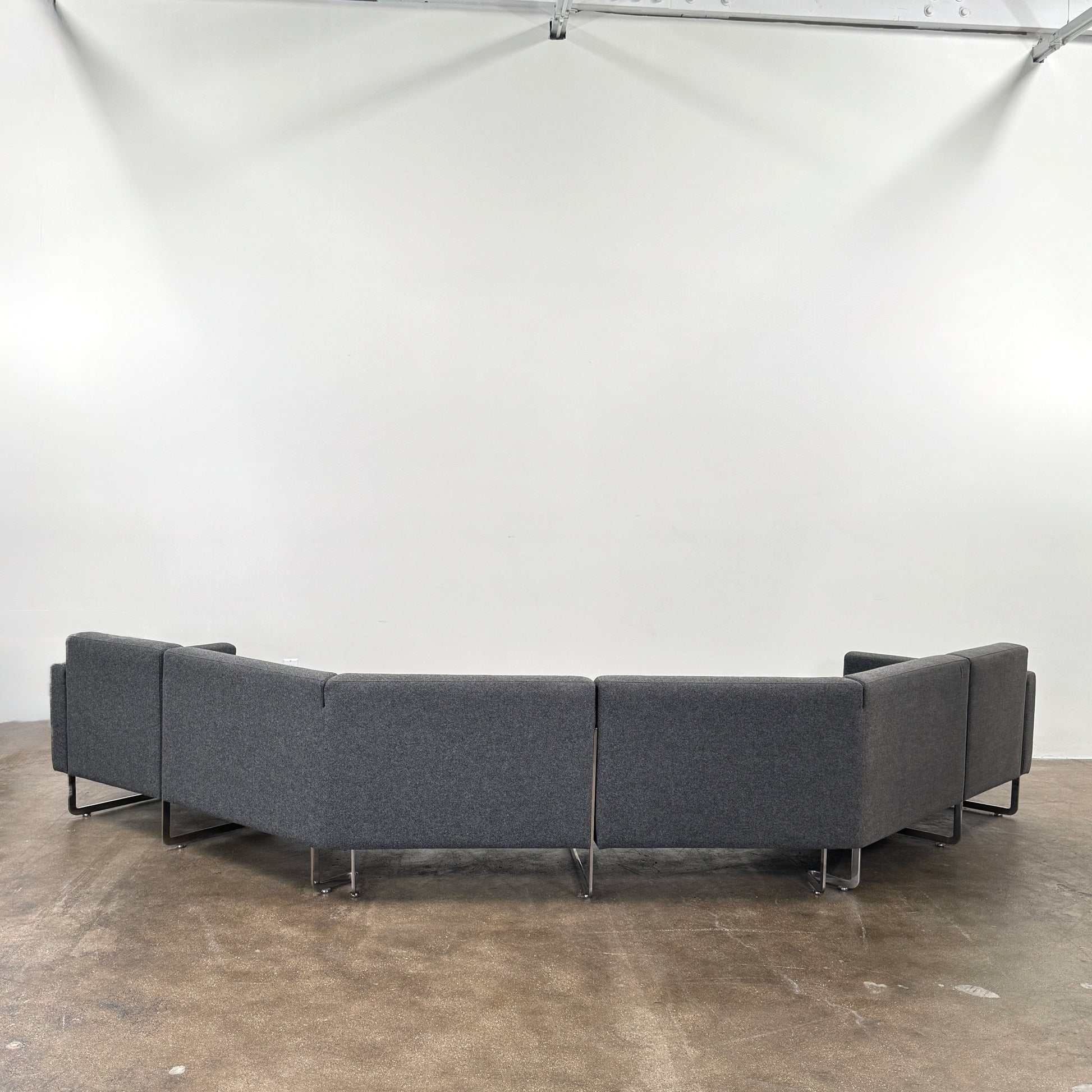 The Artifort More Mare Sectional by Artifort is a modern, dark gray sectional sofa featuring a minimalist metal frame and luxurious gray wool upholstery inspired by René Holten’s design, set against a plain white background.