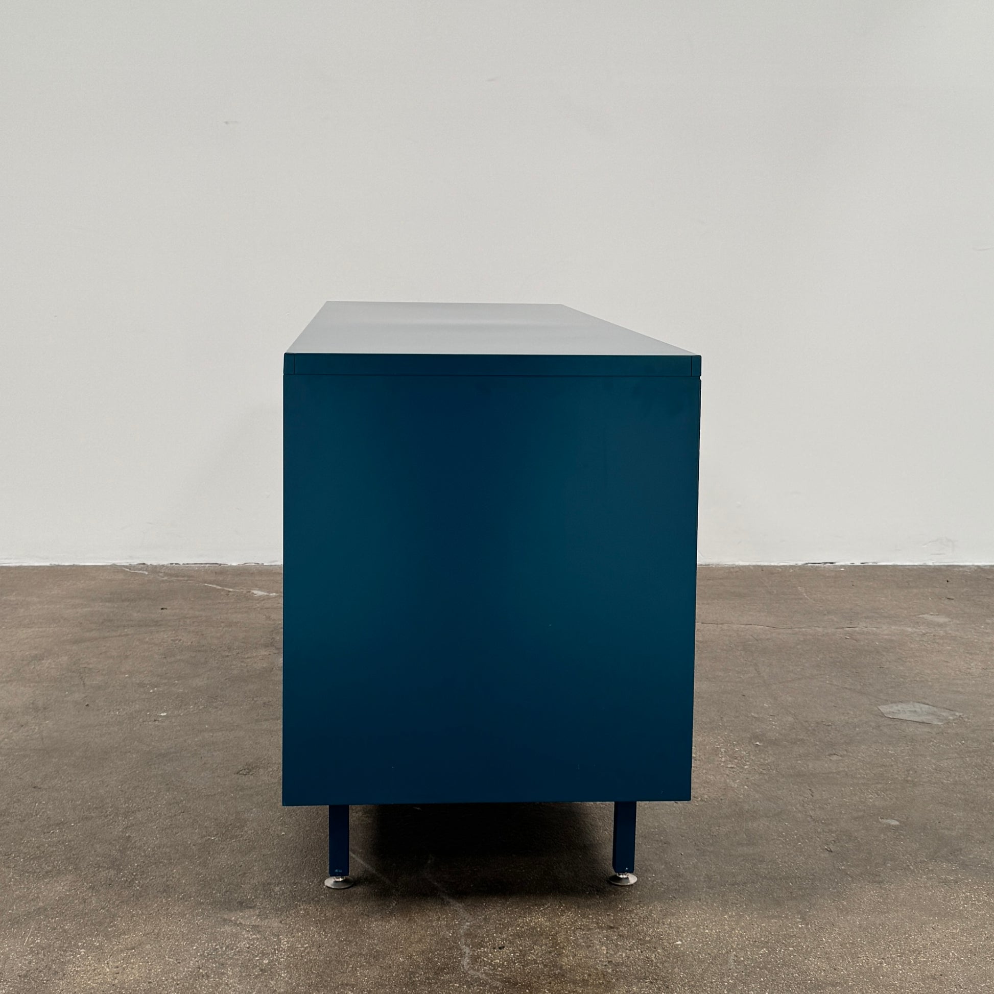 A blue metal Heartwork Active Duty Storage Credenza with two doors, a central lock, and four legs stands against a plain white background—this Heartwork piece offers durable construction ideal for workplace storage.