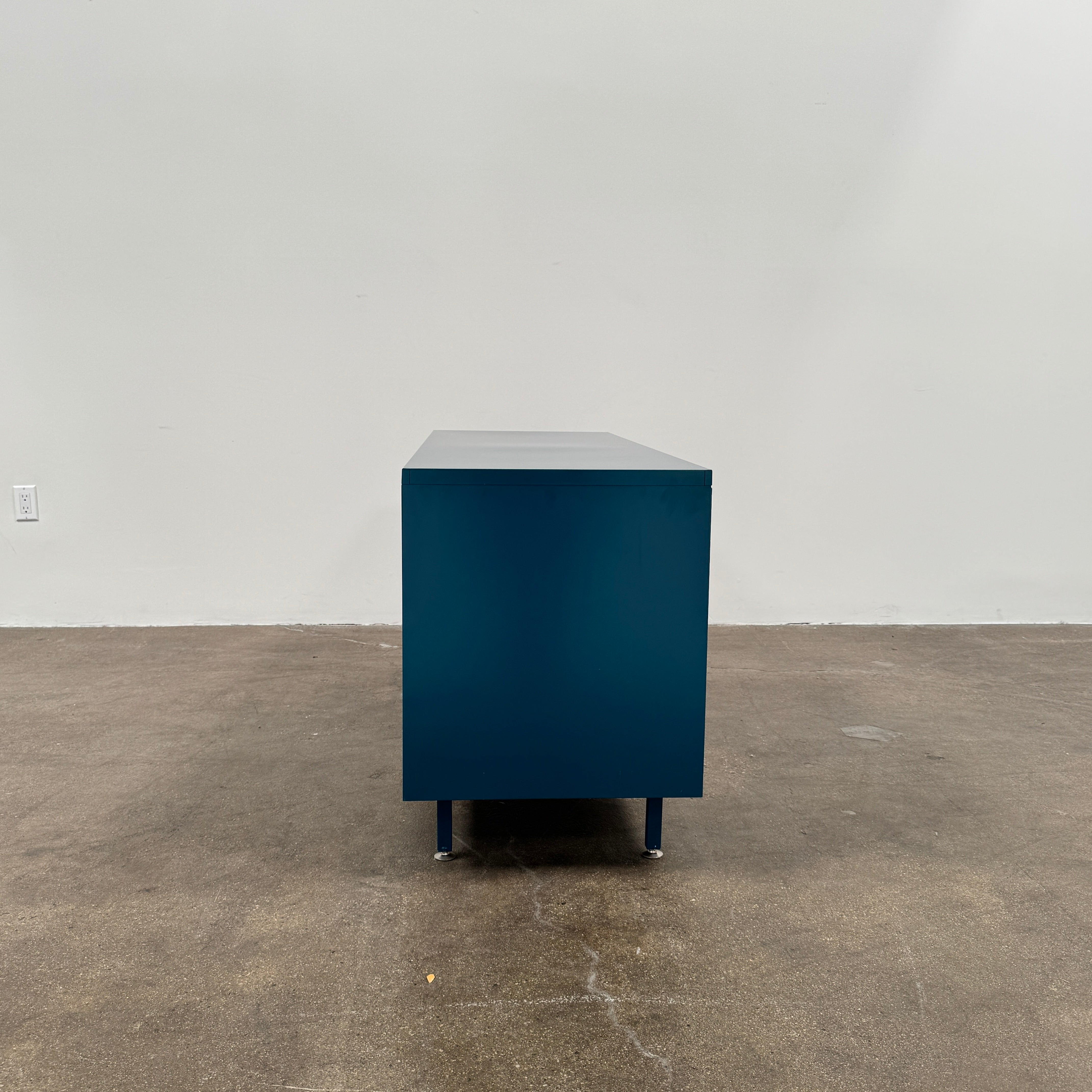 A blue metal Heartwork Active Duty Storage Credenza with two doors, a central lock, and four legs stands against a plain white background—this Heartwork piece offers durable construction ideal for workplace storage.