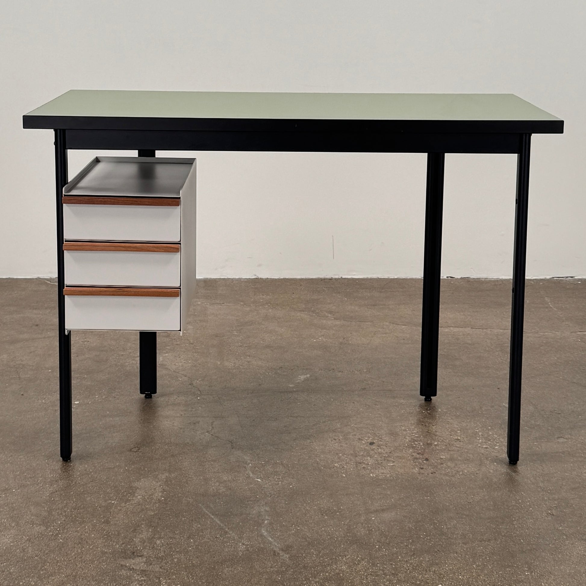 The Herman Miller Mode Desk by Herman Miller features a rectangular green tabletop, black legs, and three white drawers mounted underneath the left side—perfect as a compact desk for a minimalist workspace.
