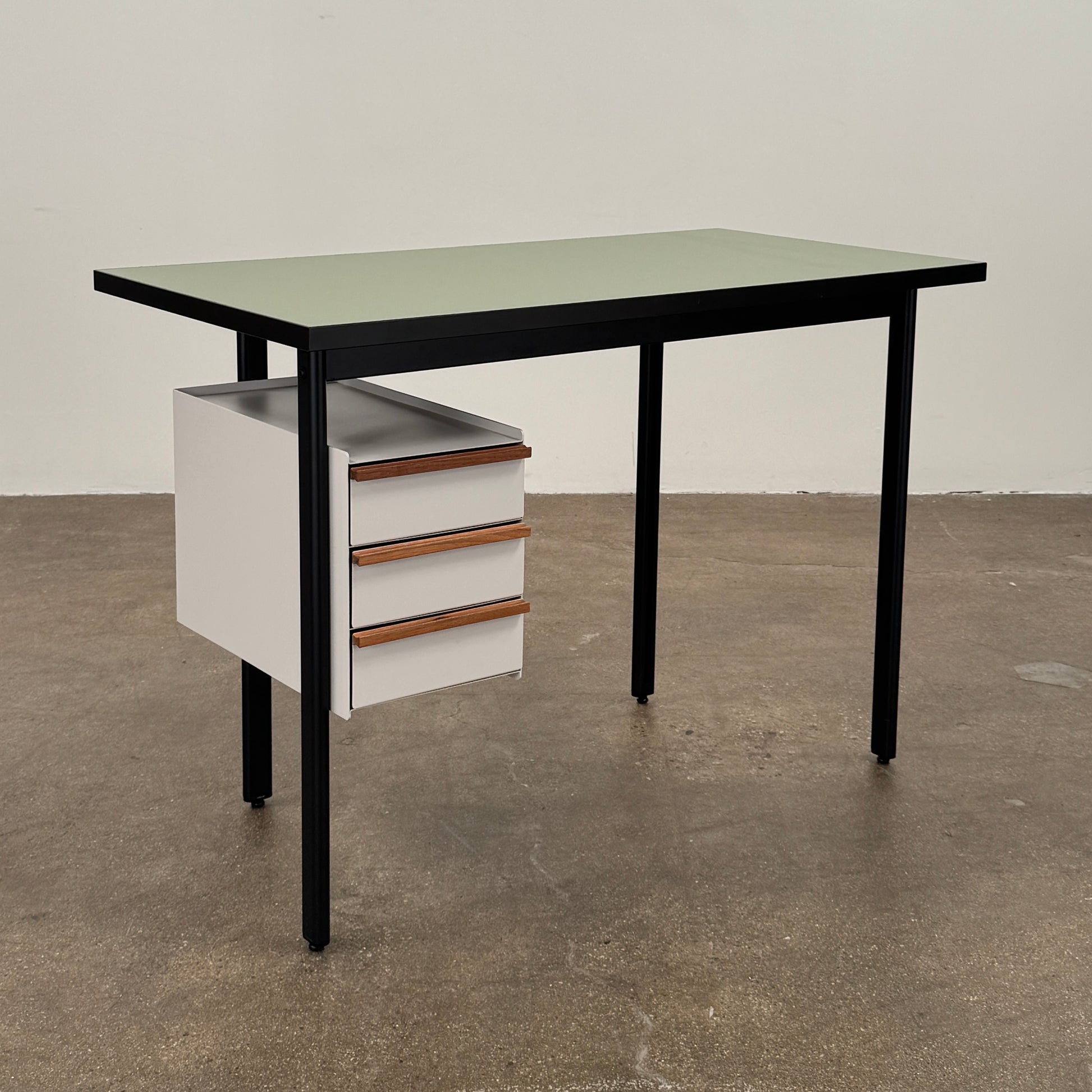 The Herman Miller Mode Desk by Herman Miller features a rectangular green tabletop, black legs, and three white drawers mounted underneath the left side—perfect as a compact desk for a minimalist workspace.