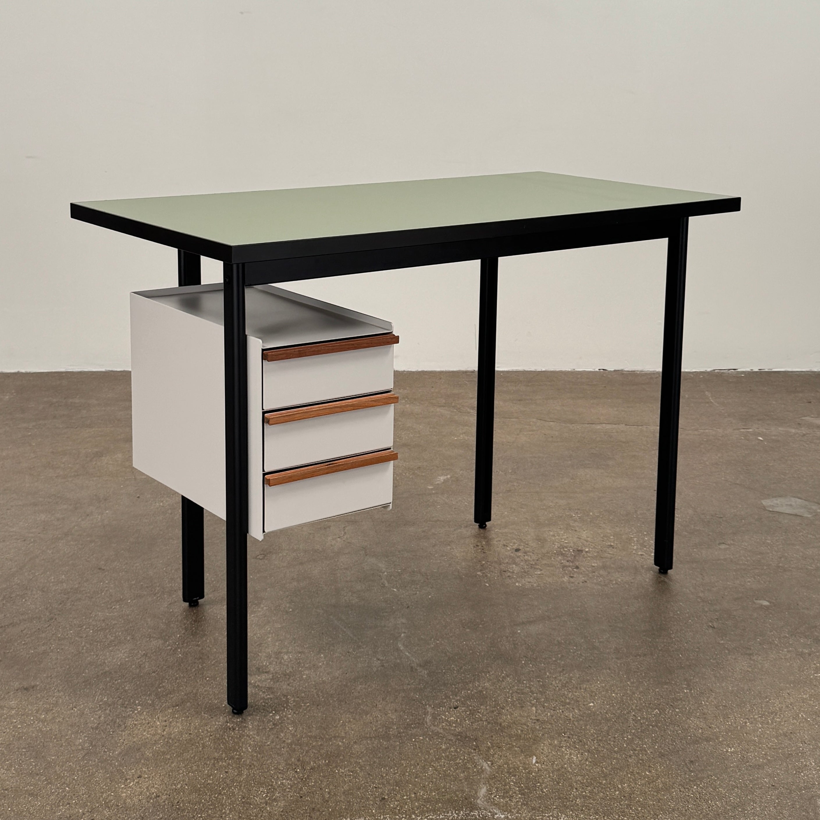 The Herman Miller Mode Desk by Herman Miller features a rectangular green tabletop, black legs, and three white drawers mounted underneath the left side—perfect as a compact desk for a minimalist workspace.